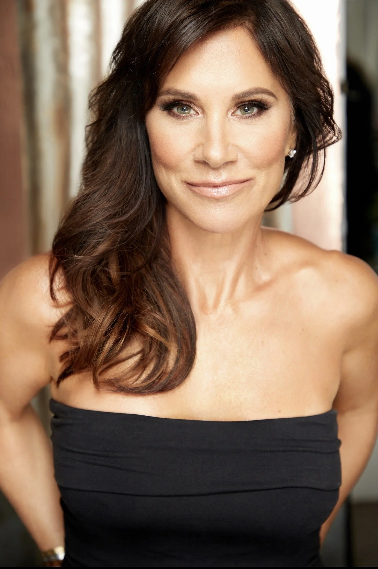 Celebrity makeup artist and Pretty Girl Makeup CEO Christina Flach wearing a strapless black gown with glamorous makeup and elegant updo hairstyle