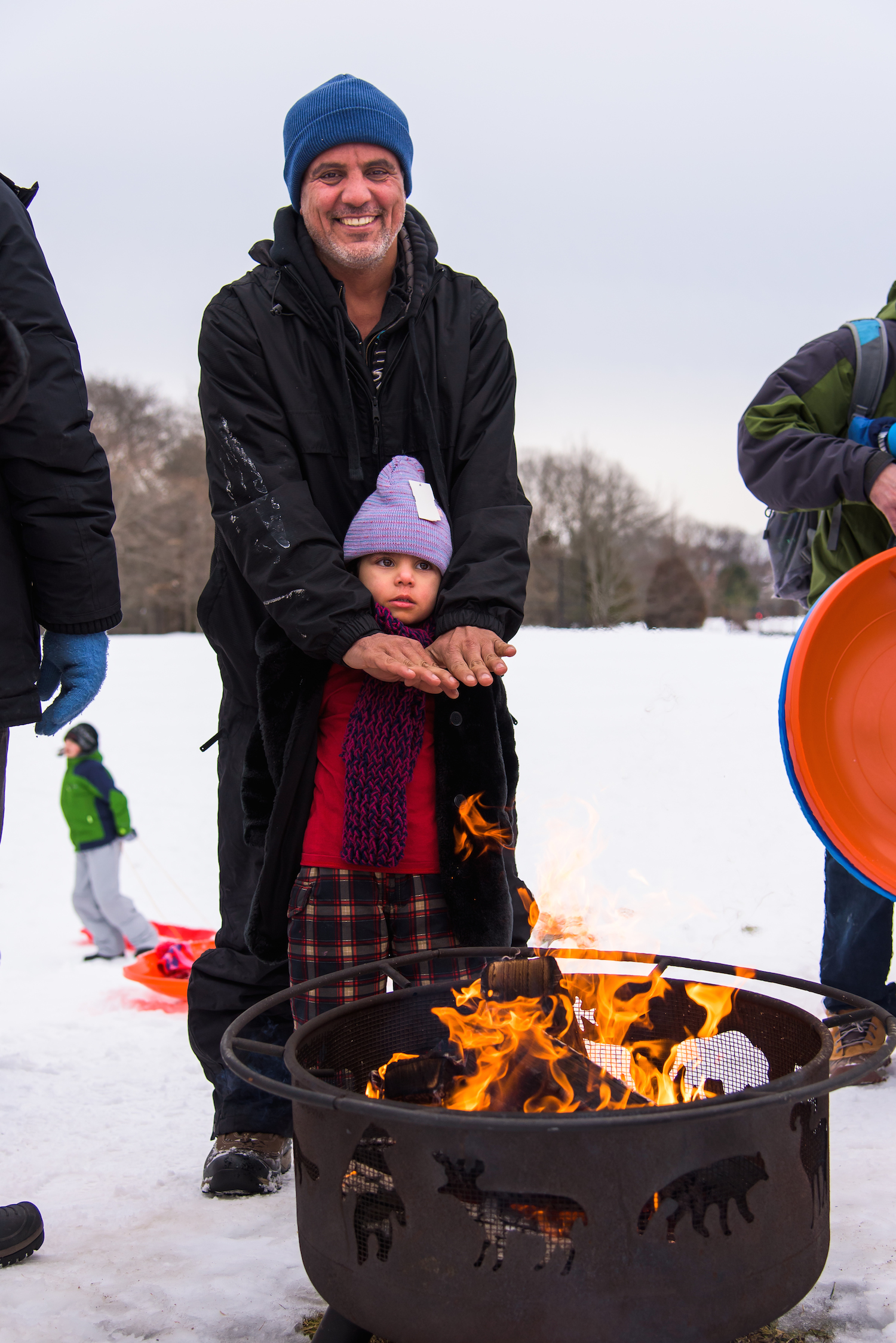 Nour Almamouri, 3, and Ahmad Almamouri, 42, of Portland by way of Iraq warm themselves by the fire.