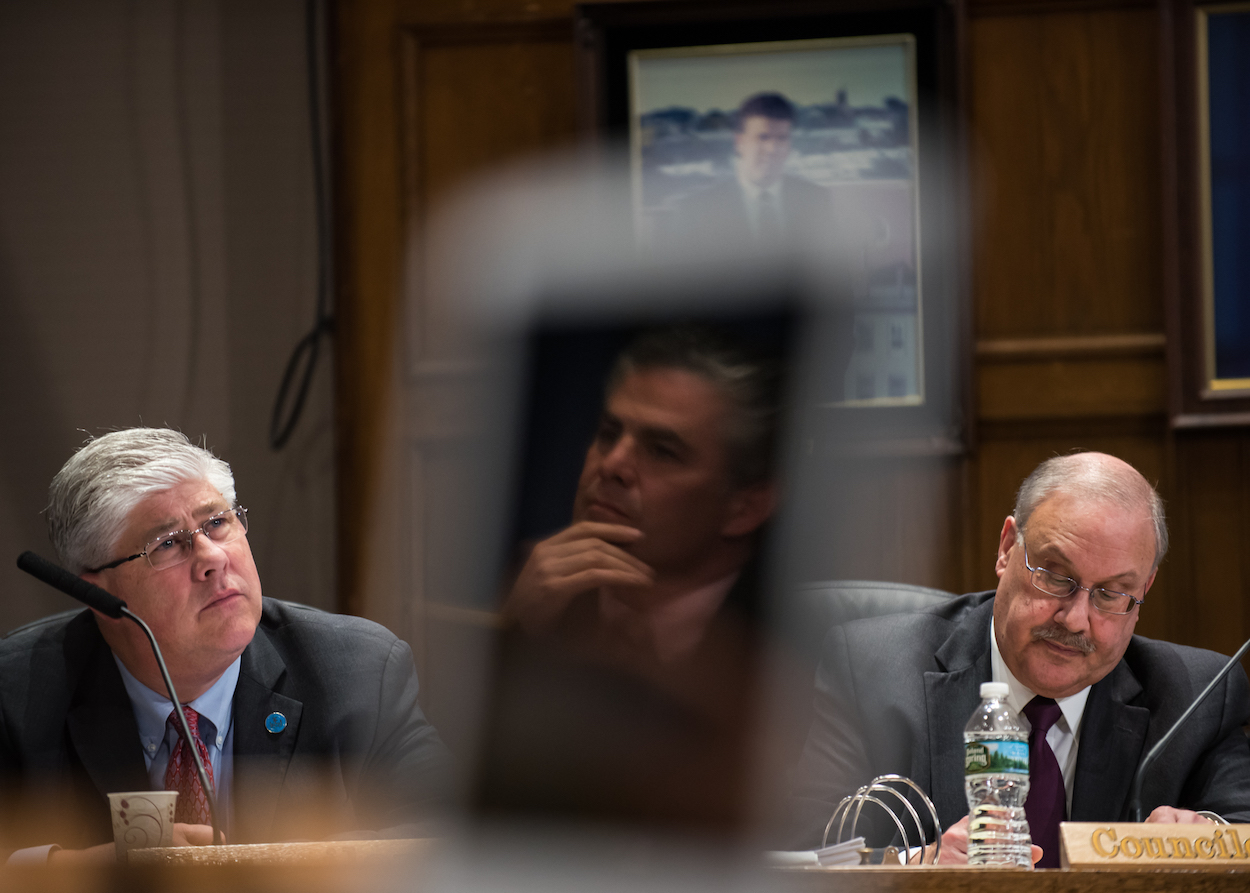 Portland city councilors Nicholas Mavodones, left, David Brenerman, and mayor Ethan Strimling, reflected in the laptop screen of councilor Brian Batson, listen to addresses from residents at a City Council meeting at Portland City Hall Monday, March 27, 2017.