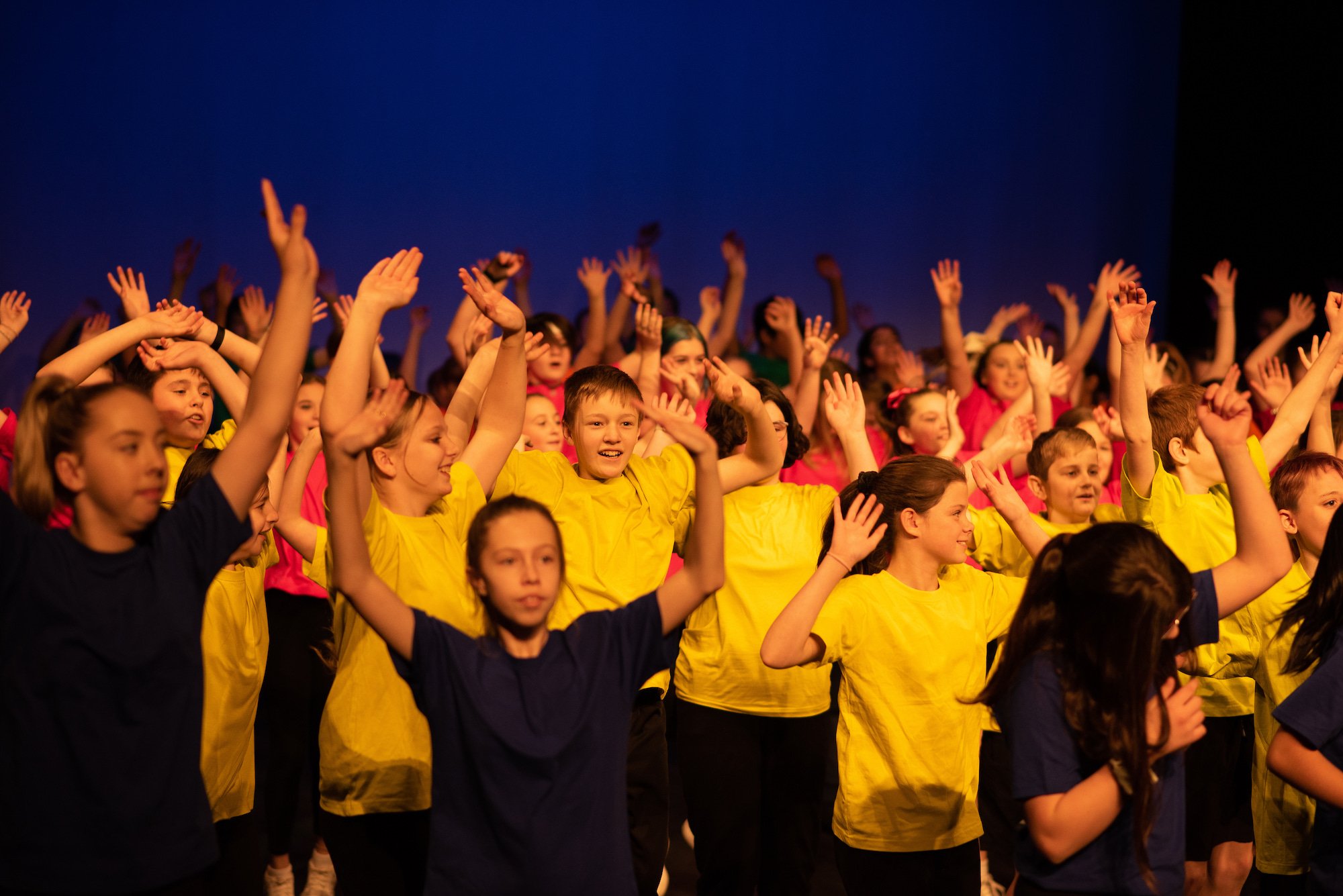  dozens of students dancing on stage joyfully arms raised 