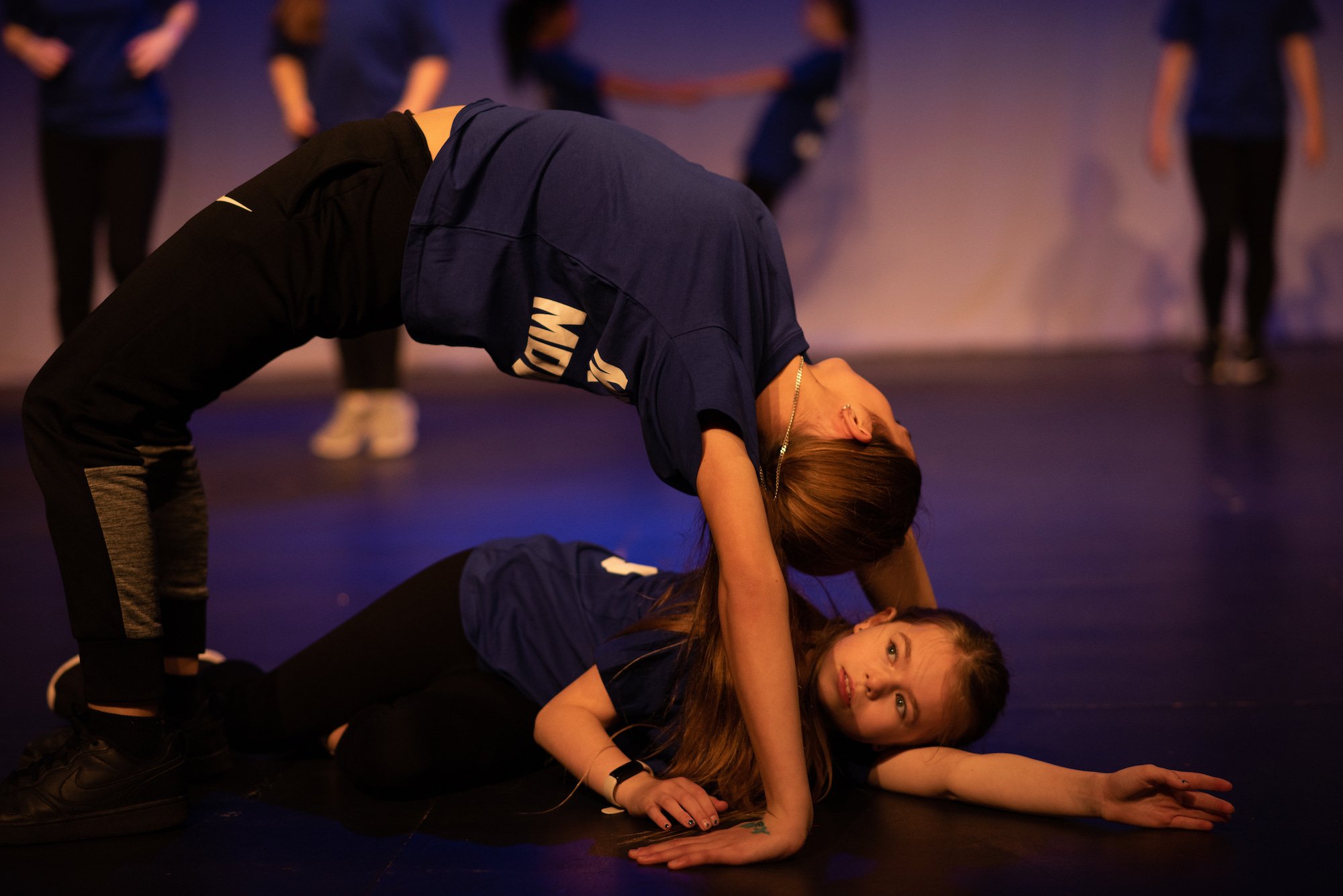  dancer in a backbend with another dancer laying underneath 
