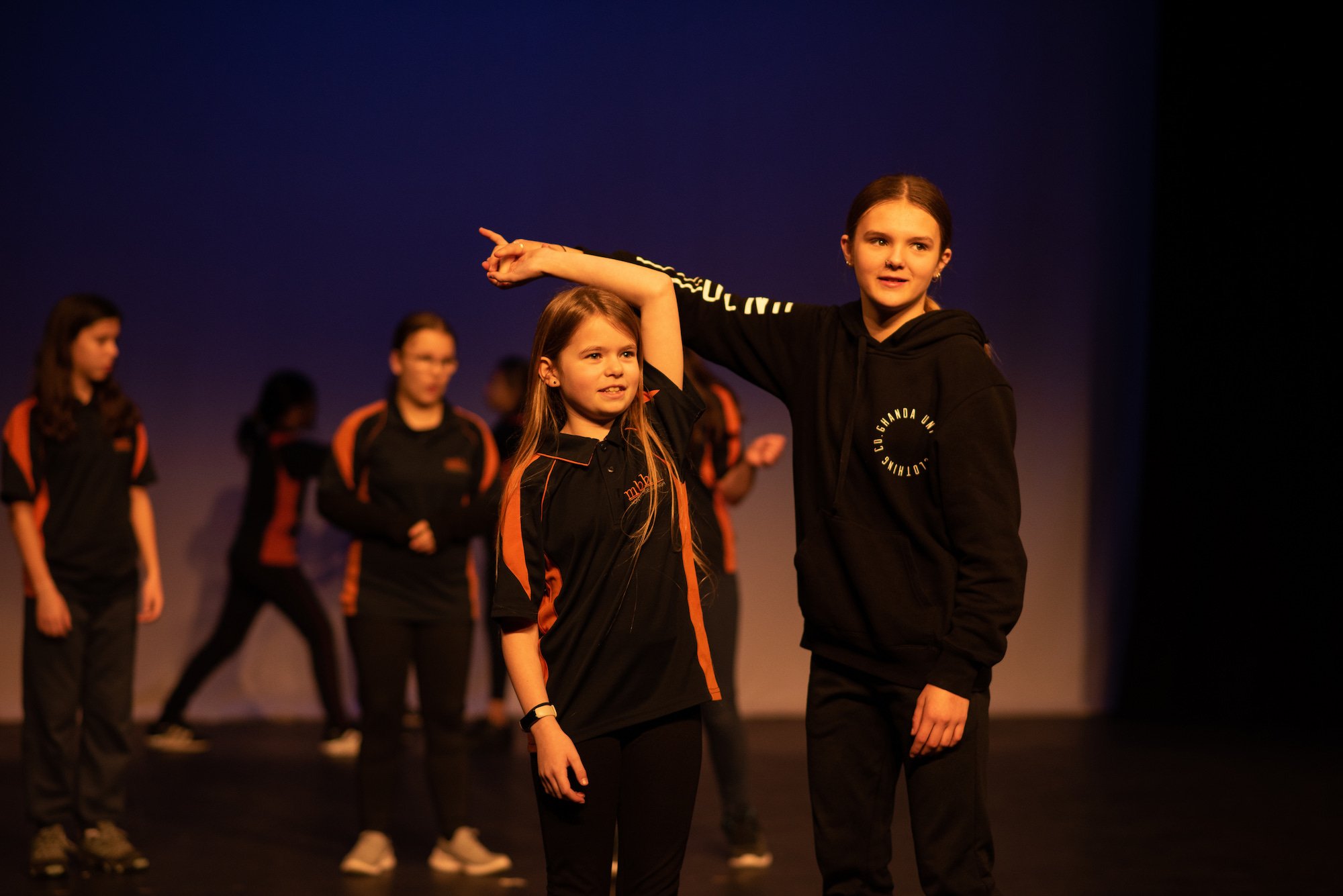  older and younger students dancing together on stage  