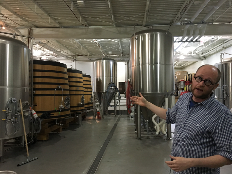 Nathan Zeender, head brewer at D.C. based Right Proper Brewing Company, standing in front their fermentation barrels. (Robin Dienel/American University)