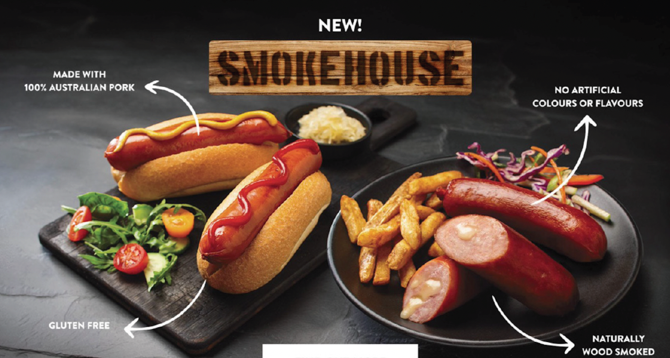 A tray of gourmet hot dogs with coleslaw, French fries, and salad, labeled as made with Australian pork, gluten-free, naturally wood smoked, with no artificial colors or flavors, and a label indicating the new smoked house style.