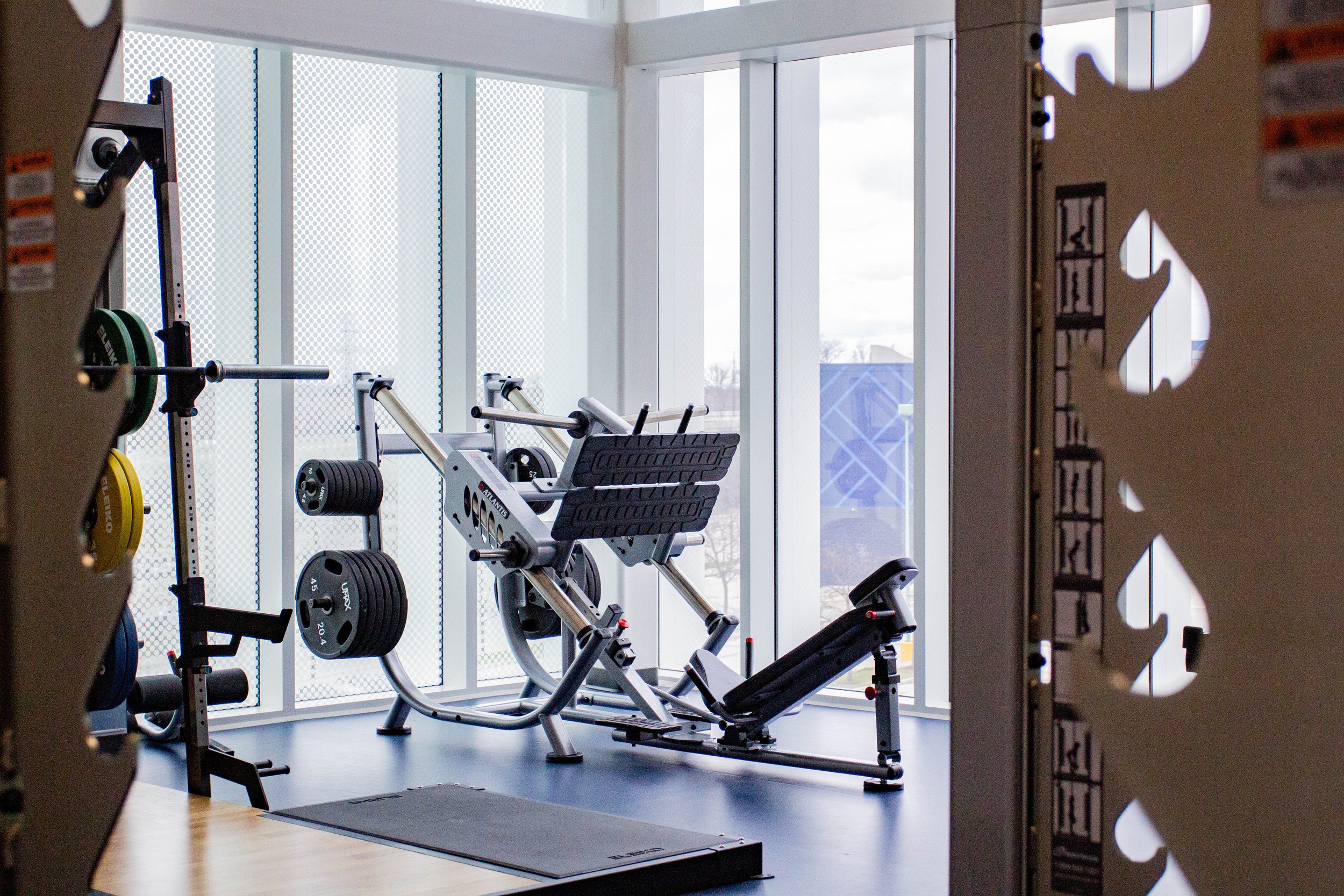  Leg press machine inside the HMC Student Centre Gym near a glass window.    