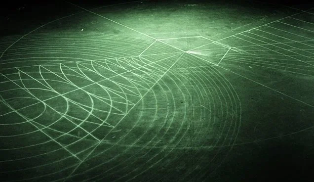 Chalkboard with geometric and wave patterns drawn in white chalk.