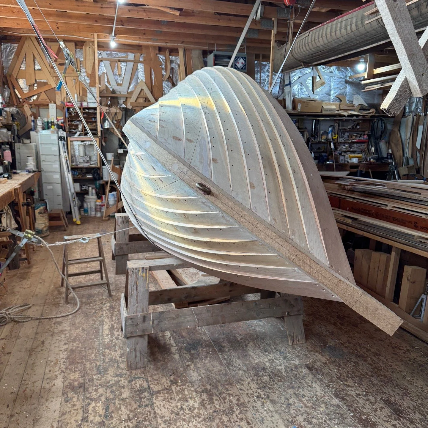In this post I turn the boat over to install the locust wear shoe and paint the bottom. In the first photo, I a turning the boat over with the help of about 3 come-alongs . Second photo shows the boat set up. Third photo shows the locust wear shoe be