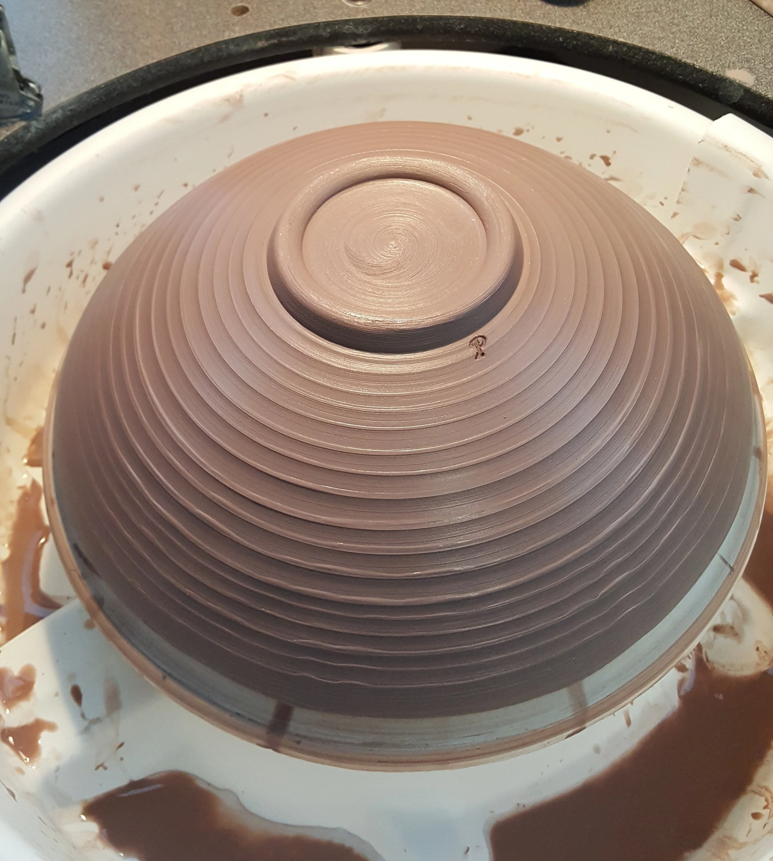 This is a perfect example of a multi process piece. The clay was rolled out into a flat piece, cut, and placed over a bowl shaped plaster bat on the wheel. It was then formed and compressed and a foot was formed with the fingers. The bowl is basically thrown upside down.