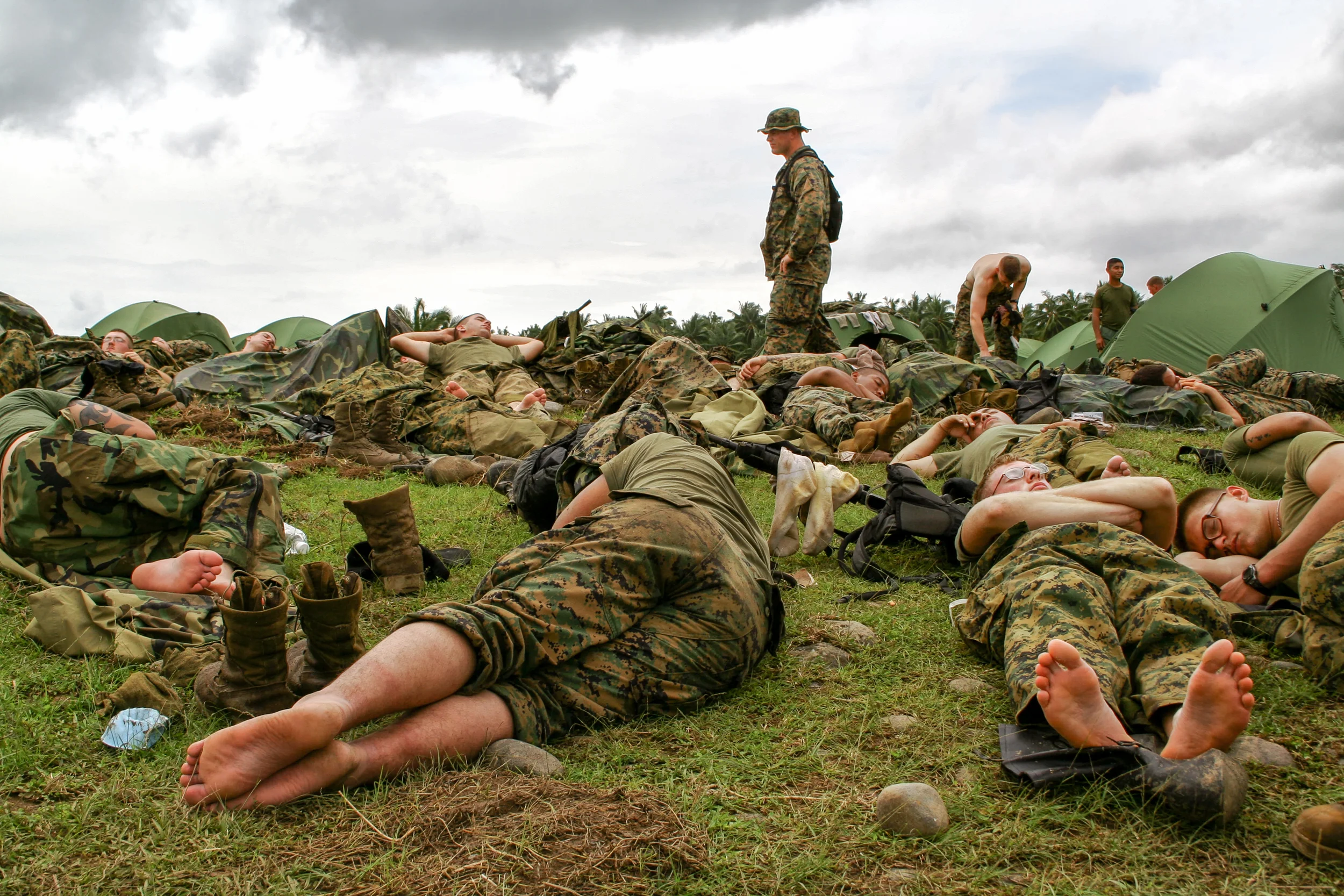 A U.S. Navy medical officer walks through a U.S. Marine encampment after a day of searching for landslide victims (Guinsaugon, Leyte, Philippines).
