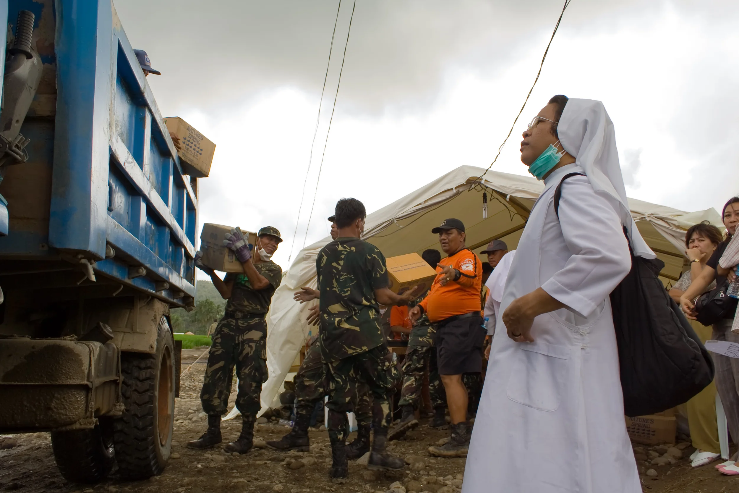 A nun watches as supplies are unloaded at the search operations area in Guinsaugon, Leyte, Philippines.