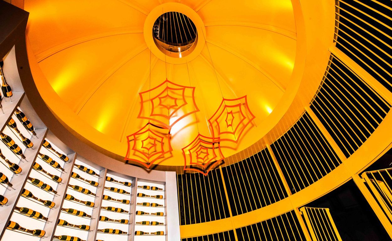 Interno Cupola: Dettaglio interno cupola illuminata con fari a LED e parete retro illuminata con installazione bottiglie Veuve Clicquot.