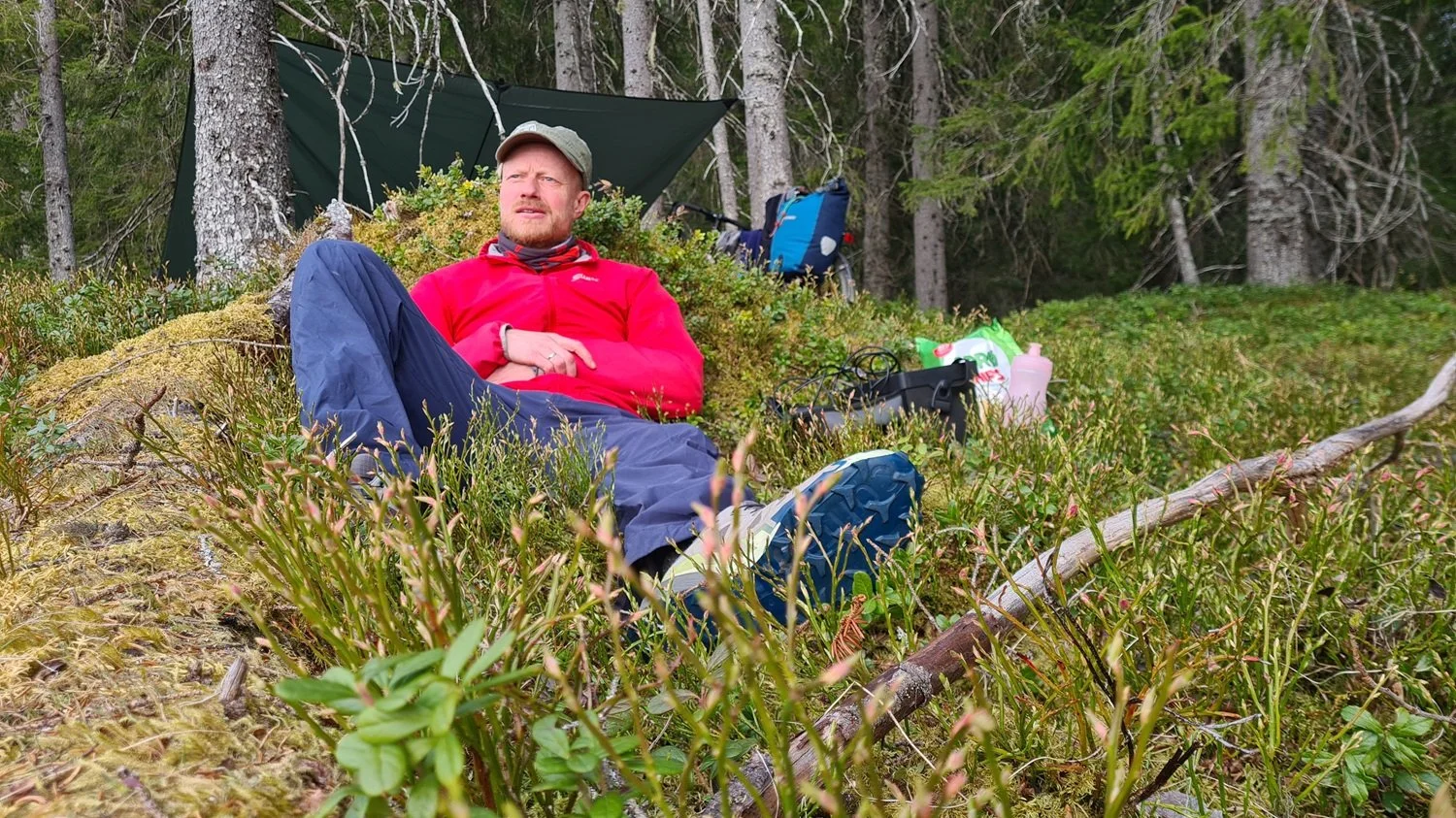 Mann sitter på bakken i skogen.