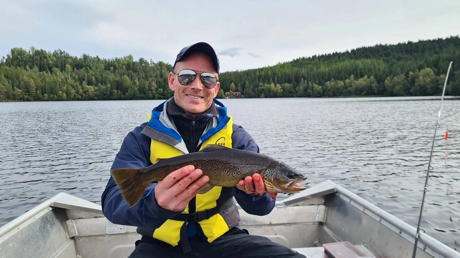 Mann smiler etter å ha fått en stor ørret.