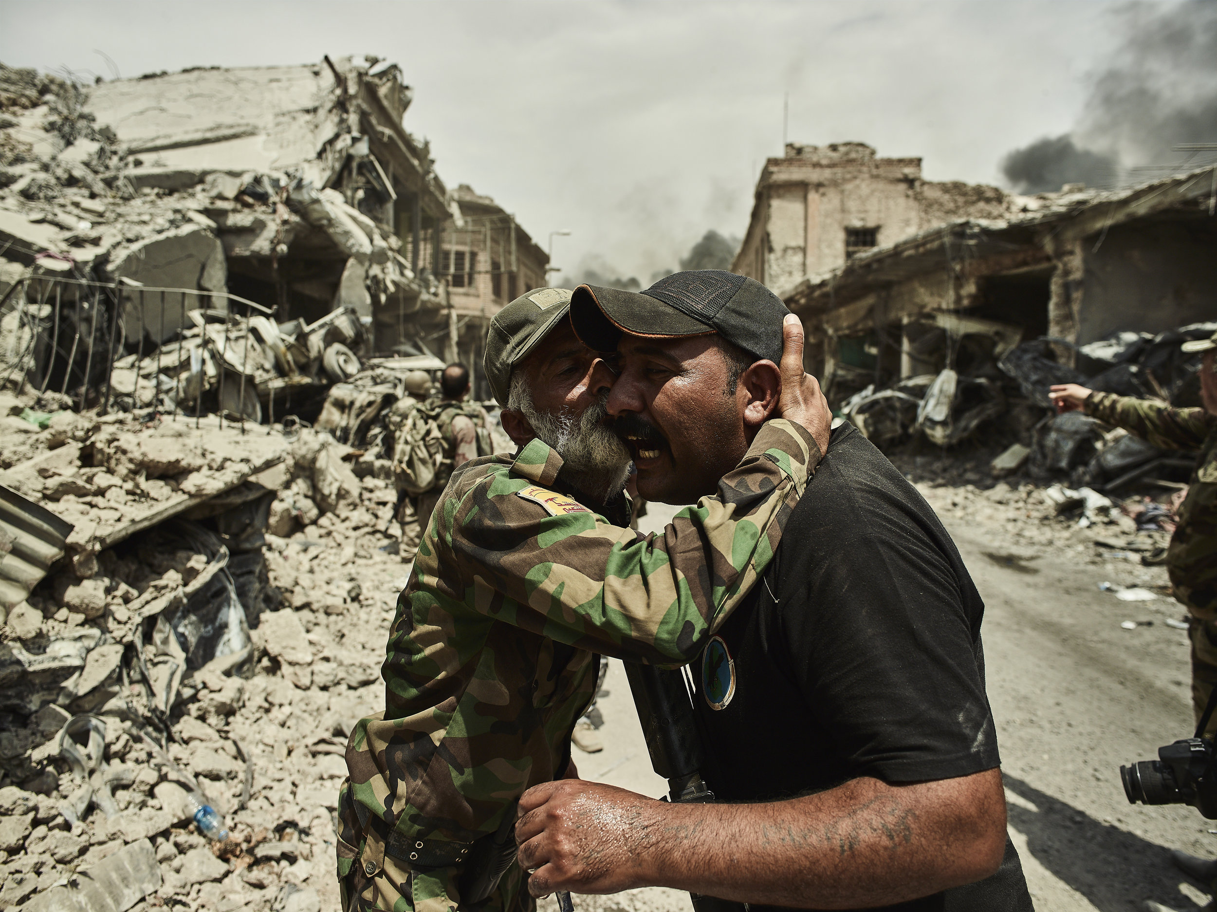 Two men embrace in the middle of battle, West Mosul