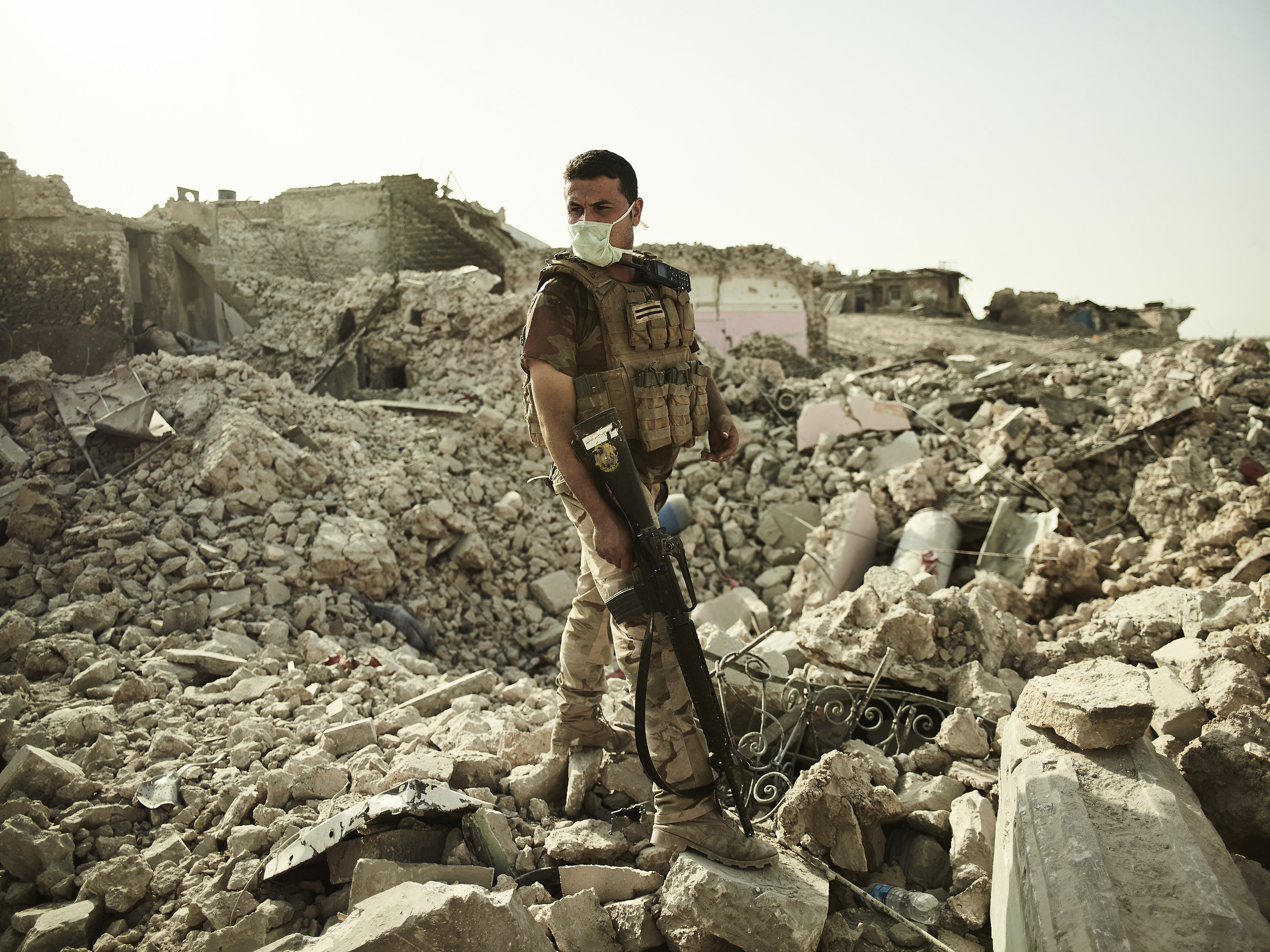 A soldier stands in the crater of an airstrike, West Mosul