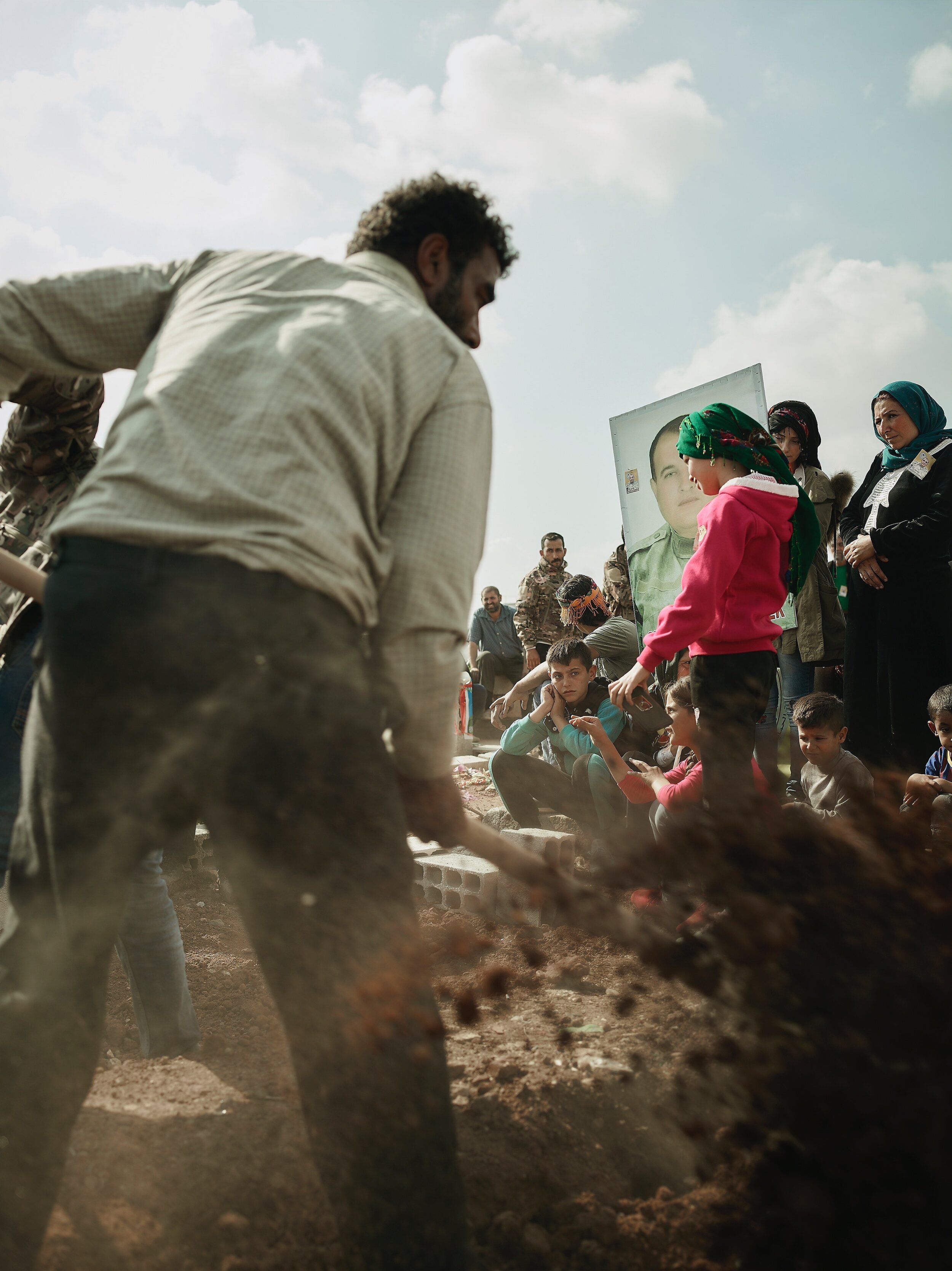 A young boy watches as his father is buried in the YPG cemetery in Qamishlo