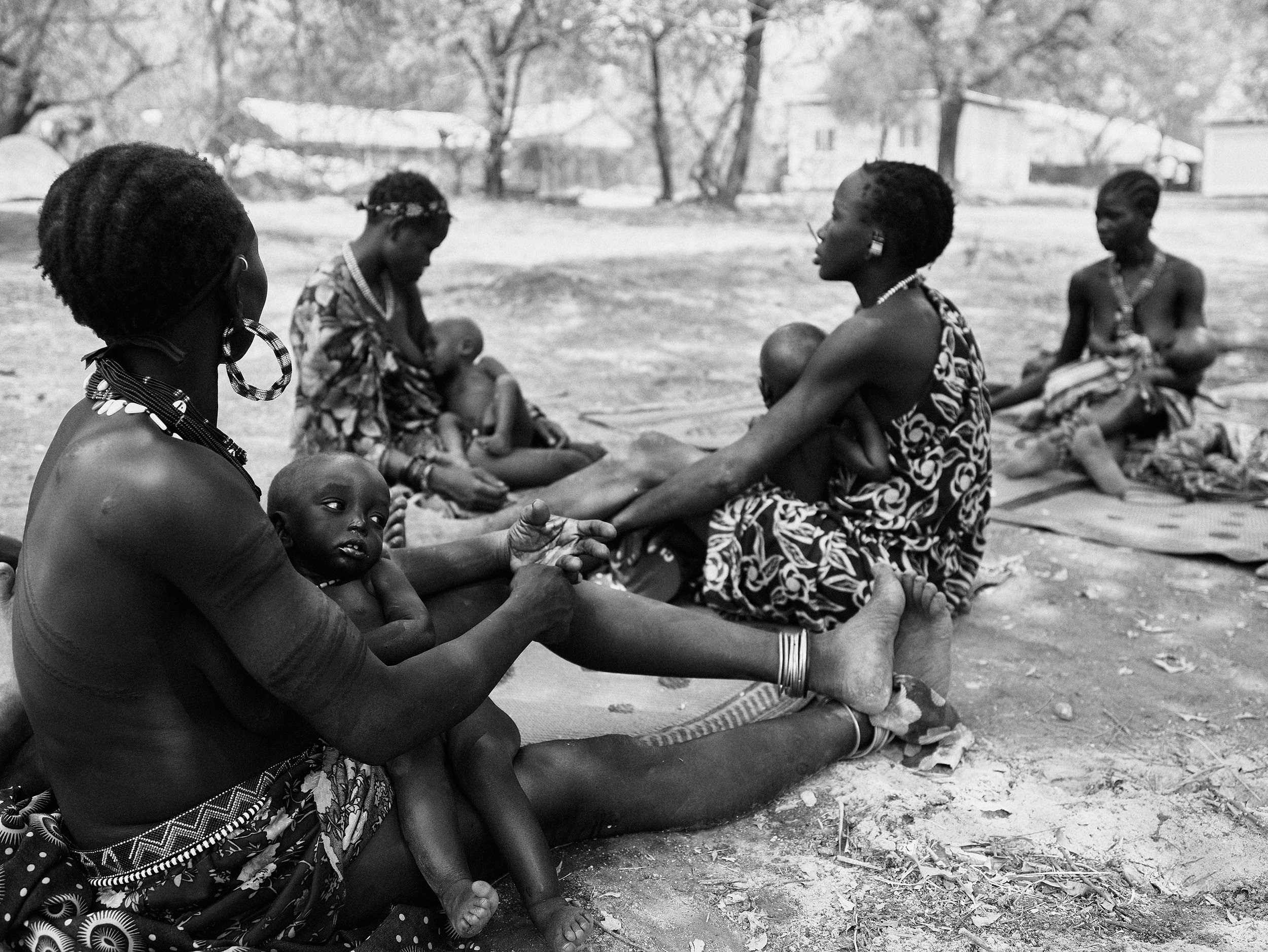 Mothers and malnourished children wait outside a malnutrition screening point in Boma, South Sudan