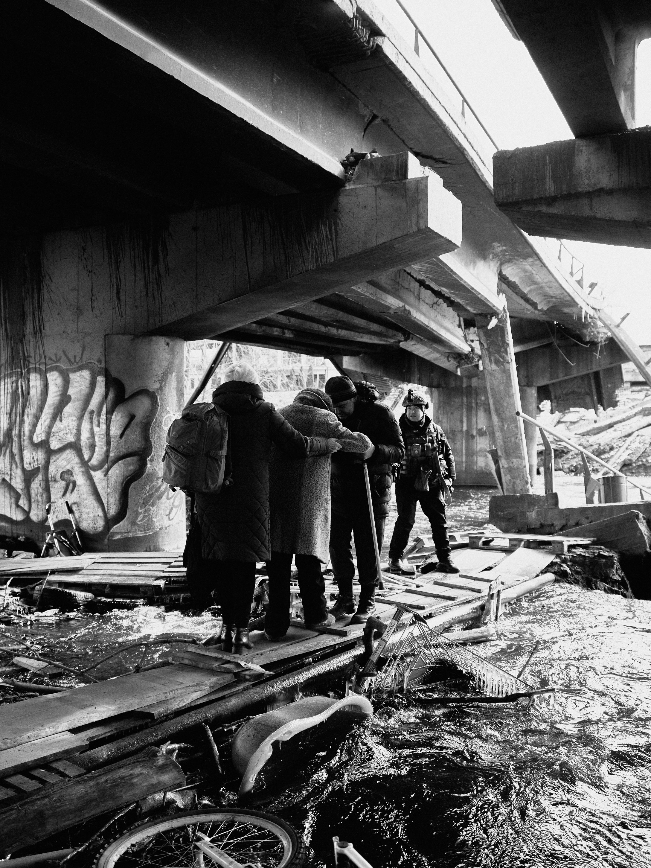 Civilians flee across a destroyed bridge in Irpin, Kyiv Oblast