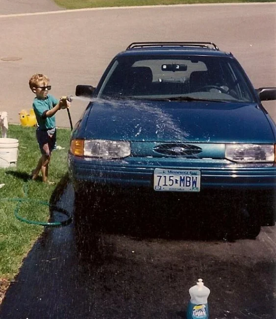 Here&nbsp;I am,&nbsp;demonstrating&nbsp;my prowess with a garden hose while washing my Dad's '95 Ford Escort LX wagon. - (Circa 1996)
