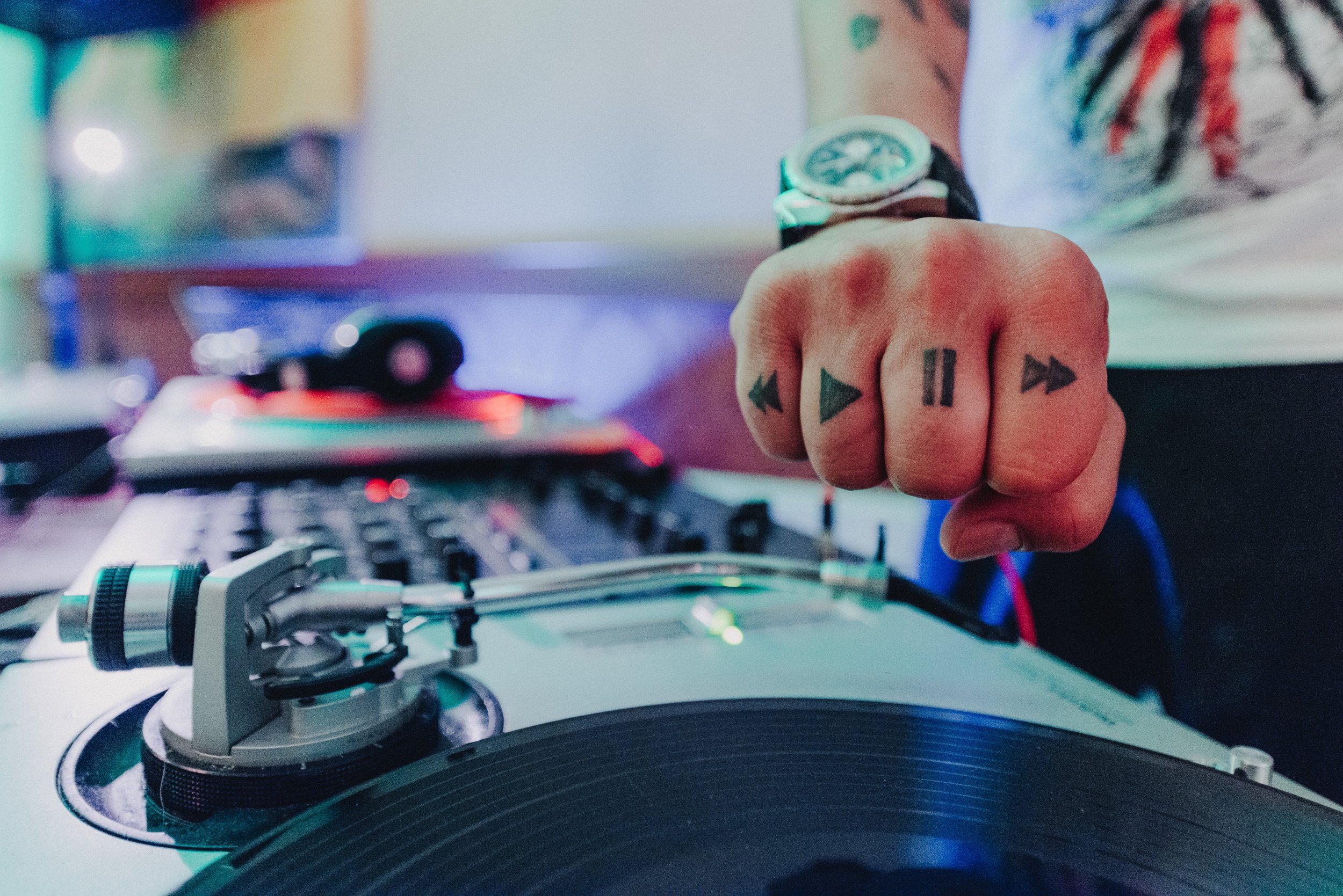  DJ mit tätowierten Händen steht am Plattenspieler 