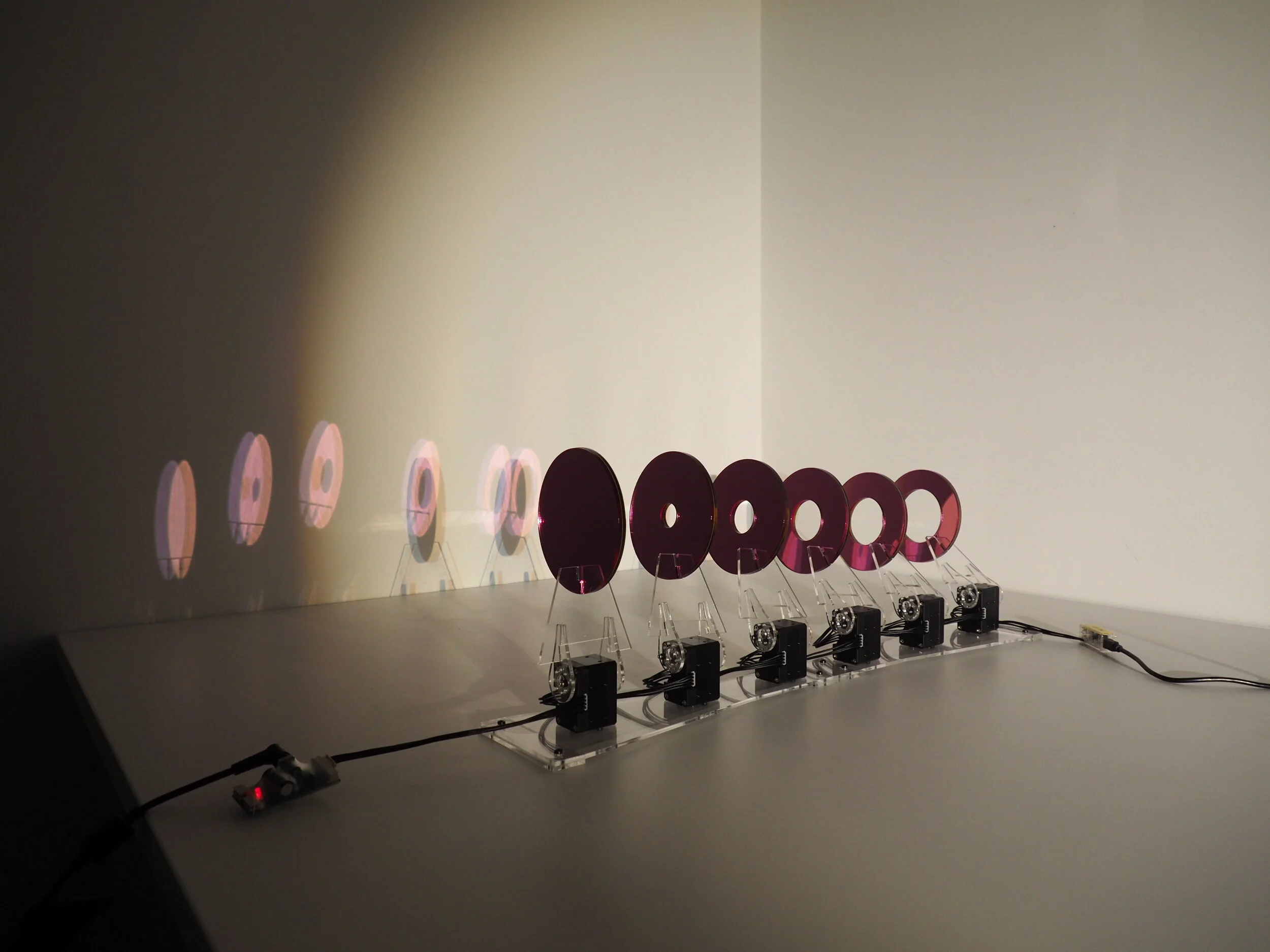  Our development of the sculptural design was to explore the phenomenon of chromatic aberration of visual perception, demonstrated by the duochrome test. The design includes a composition of a series of concentric acrylic panels lasercut in circular 