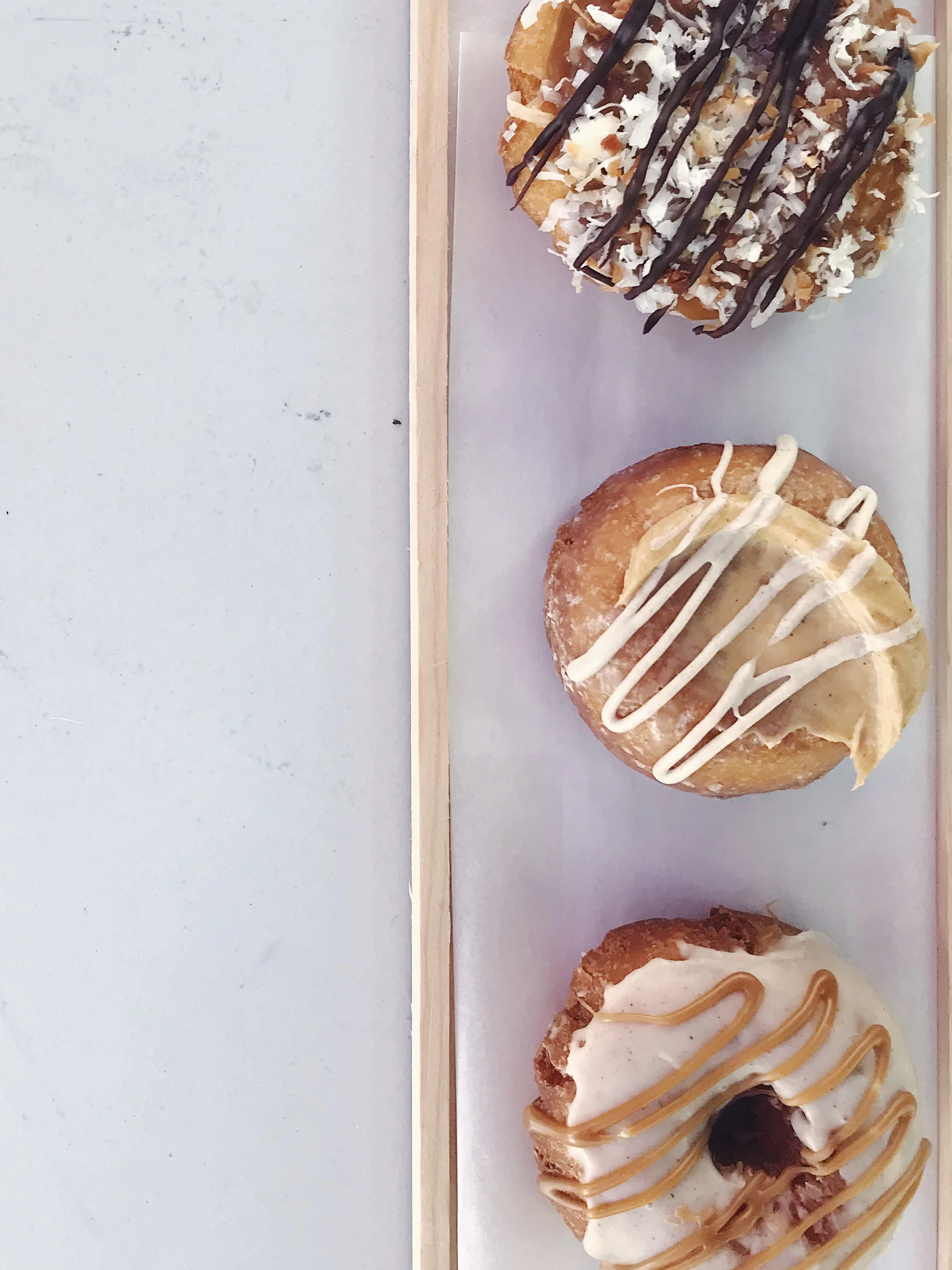 Beacon Doughnuts - pumpkin pie donut (donut in the center of photo) Super dense and moist cake donut with pumpkin filling with a light vanilla drizzle.