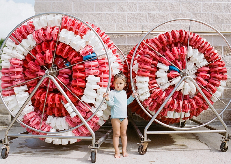  Film image of little girl standing next to lane floaties at pool by award winning Maternity, Baby, and Family Photographer, Mae Burke- Photographing families in and visiting Rockport, Port Aransas, Corpus Christi, Austin, Houston and Dallas/Fort Wor