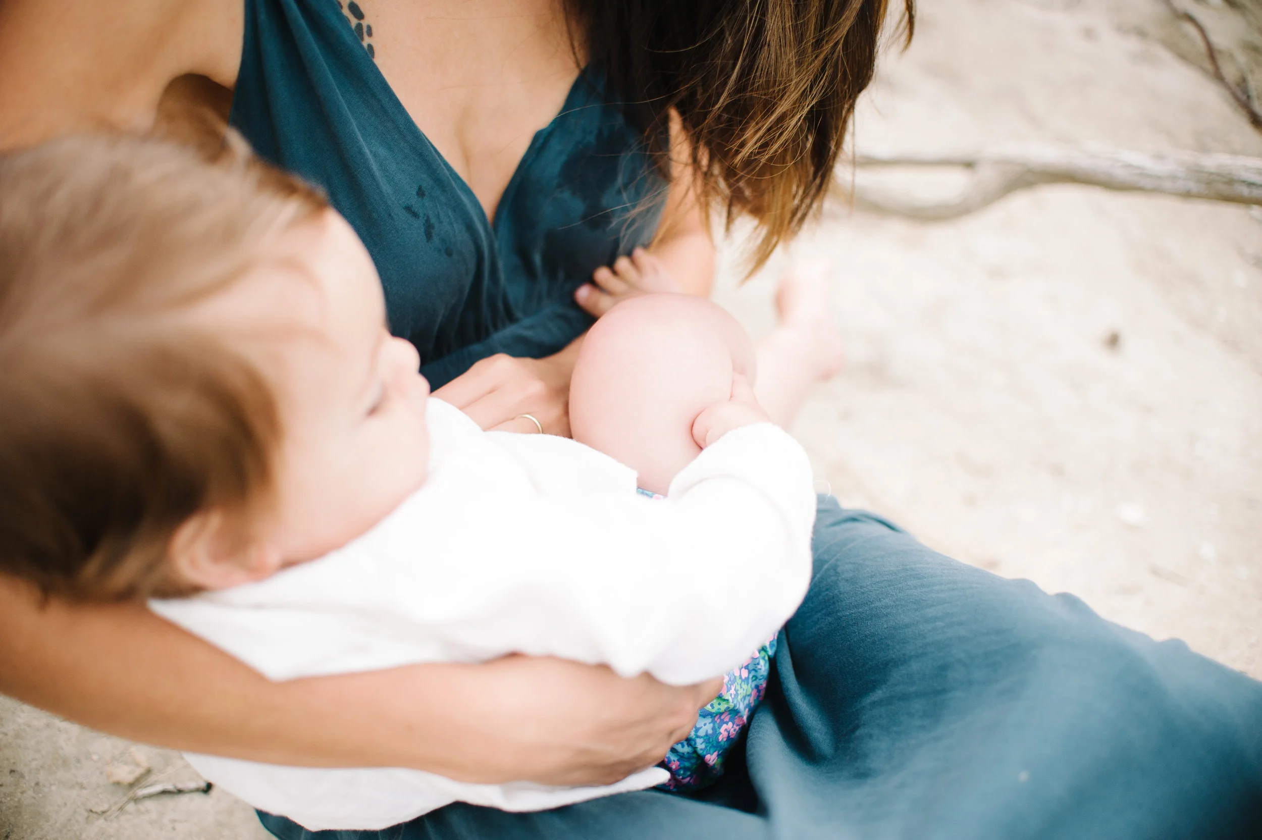  Mother holding baby on Copano Bay beach with milk stains on her dress by South Texas Award Winning Maternity, Baby, and Family Photographer, Mae Burke- Photographing families in and visiting Rockport, Port Aransas, Corpus Christi, Austin, Houston an