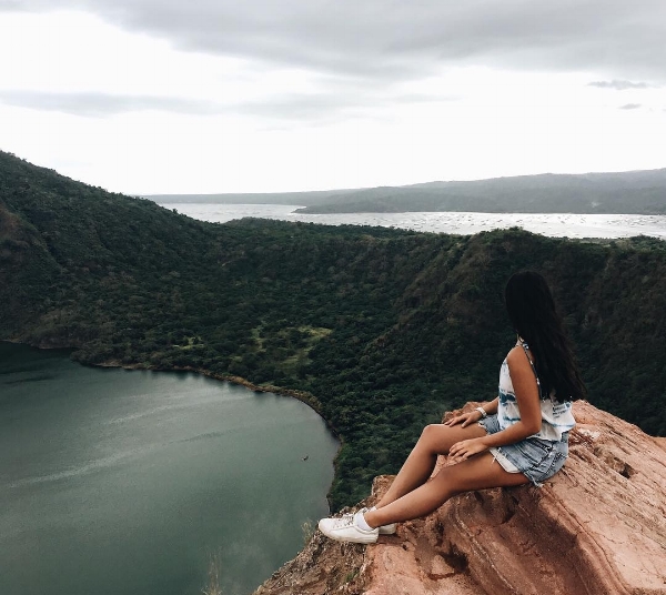 女孩坐在白色运动鞋和牛仔短裤盯着Taal Crater Lake  - 在Tagaytay，Batangas Prvovince  -  Luzon，菲律宾