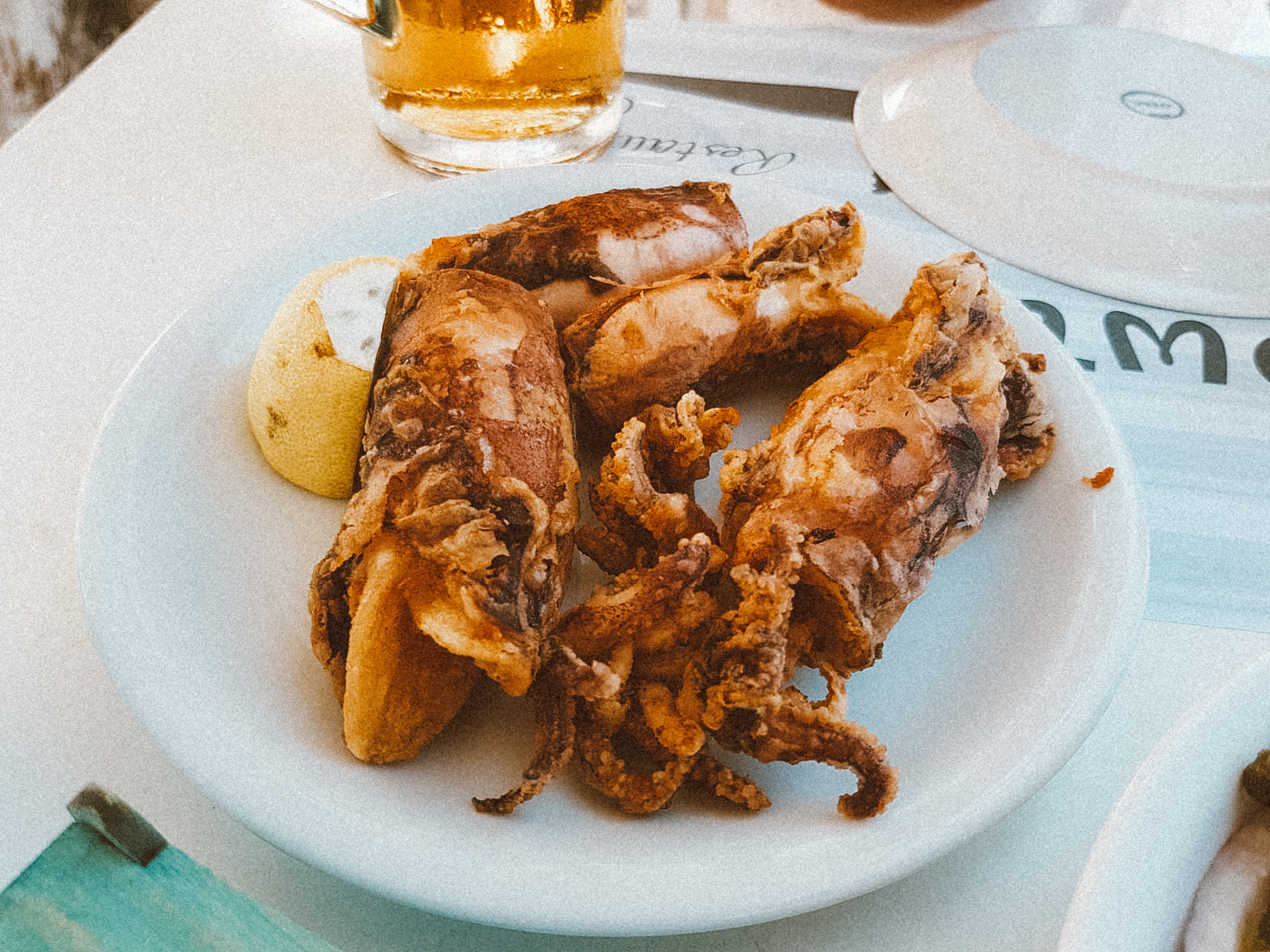 希腊米洛斯市，波洛尼亚市，白色盘子上放着鲜榨鱿鱼和一片柠檬