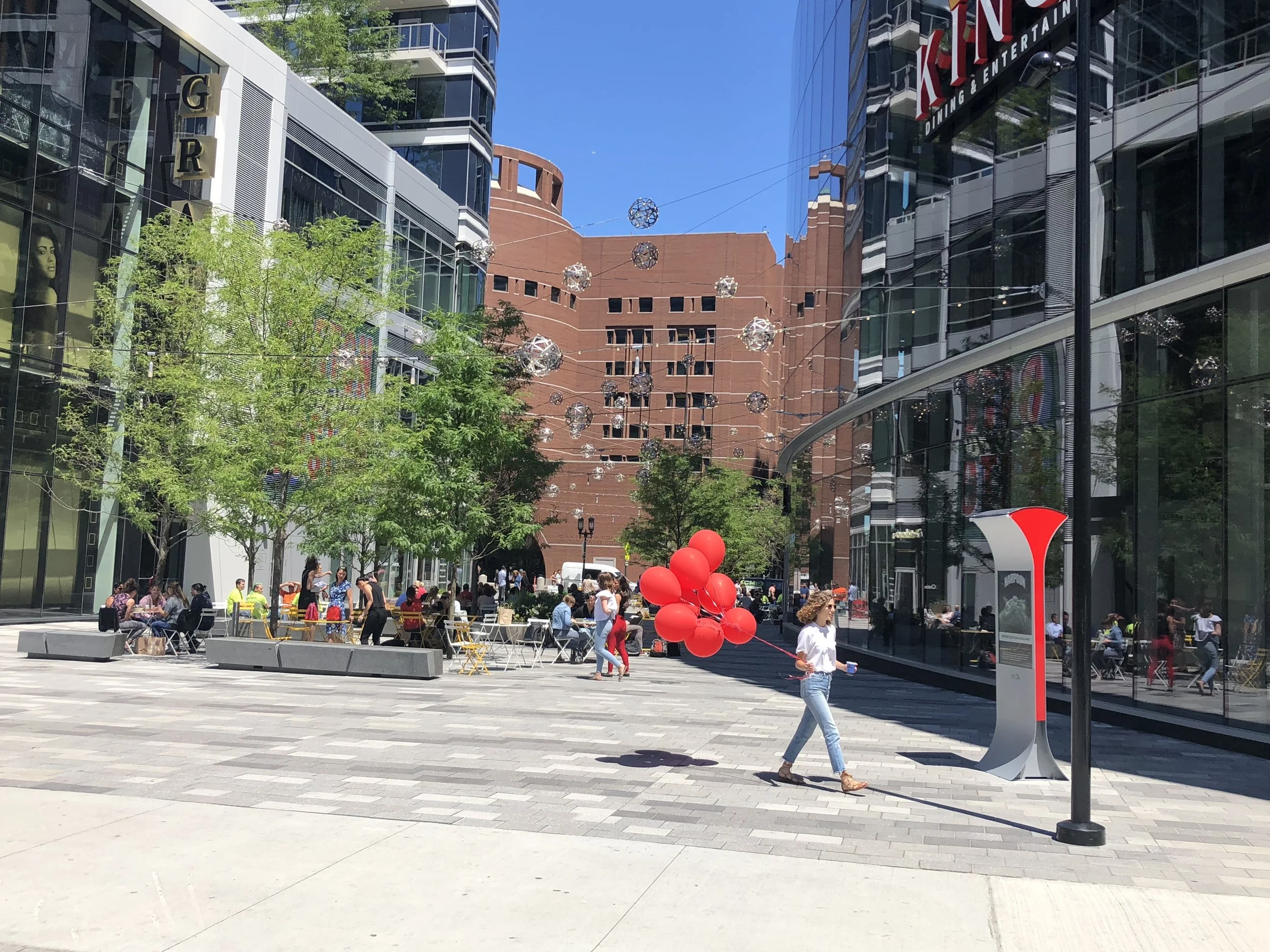 A woman strolls past the Soofa Sign in Seaport One with some balloons.