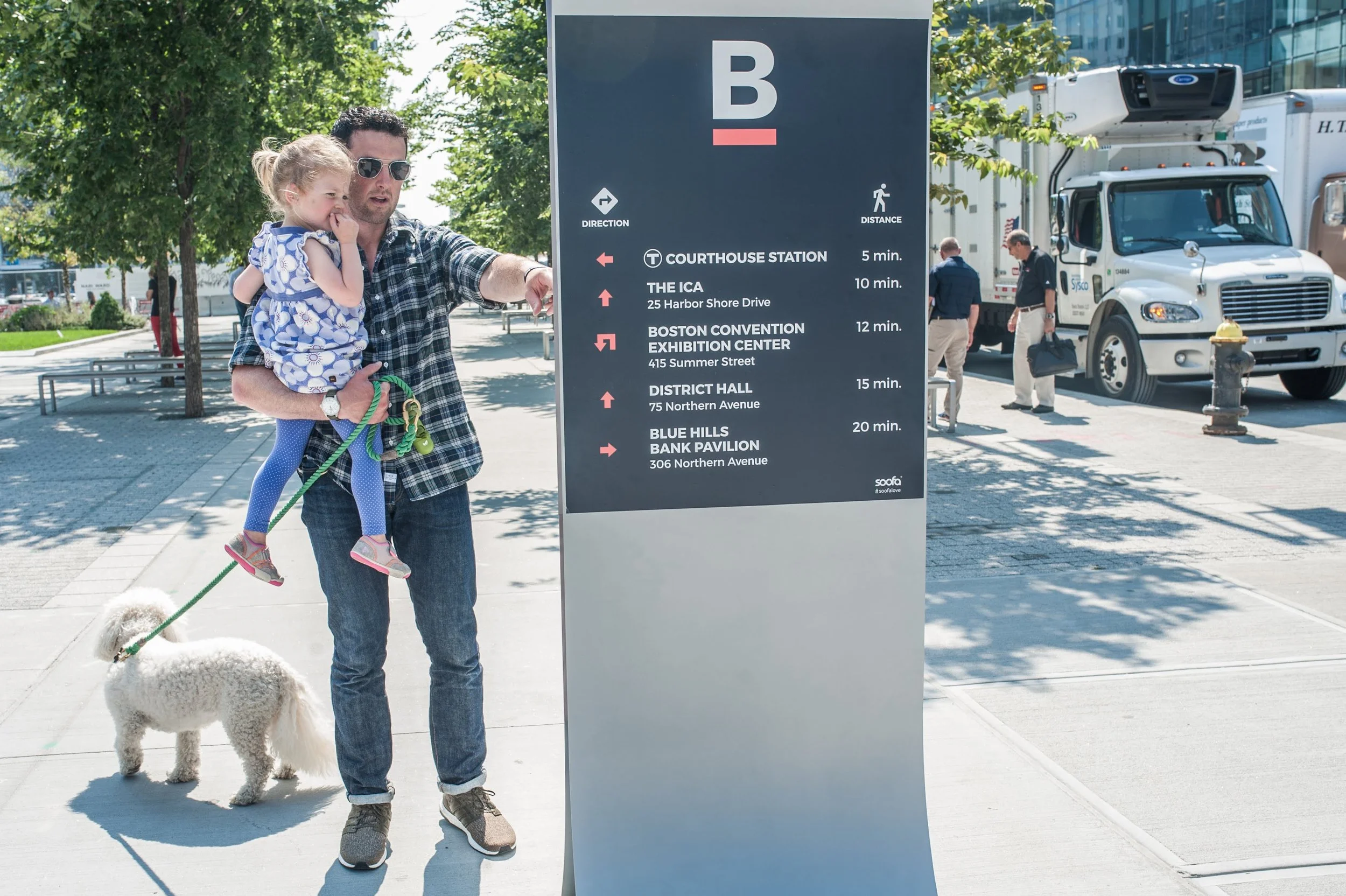 A man, child, and dog check out their neighborhood Soofa Sign