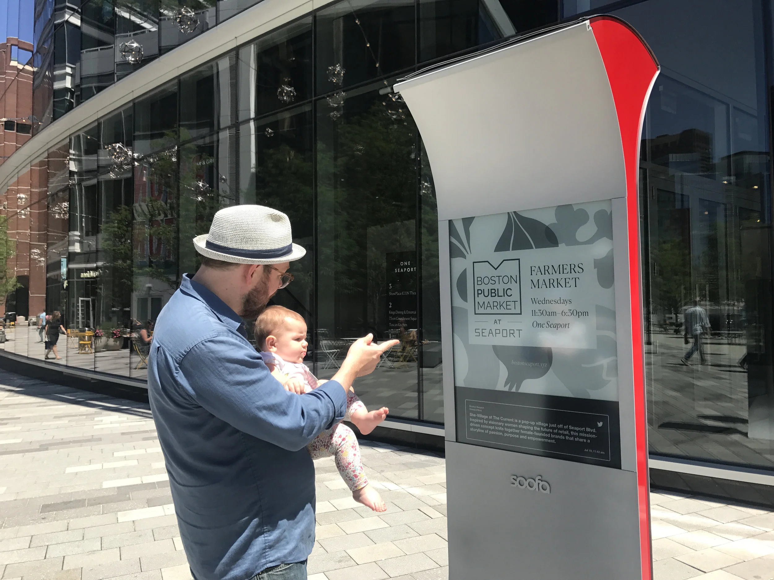 A man and baby check out Soofa Sign content