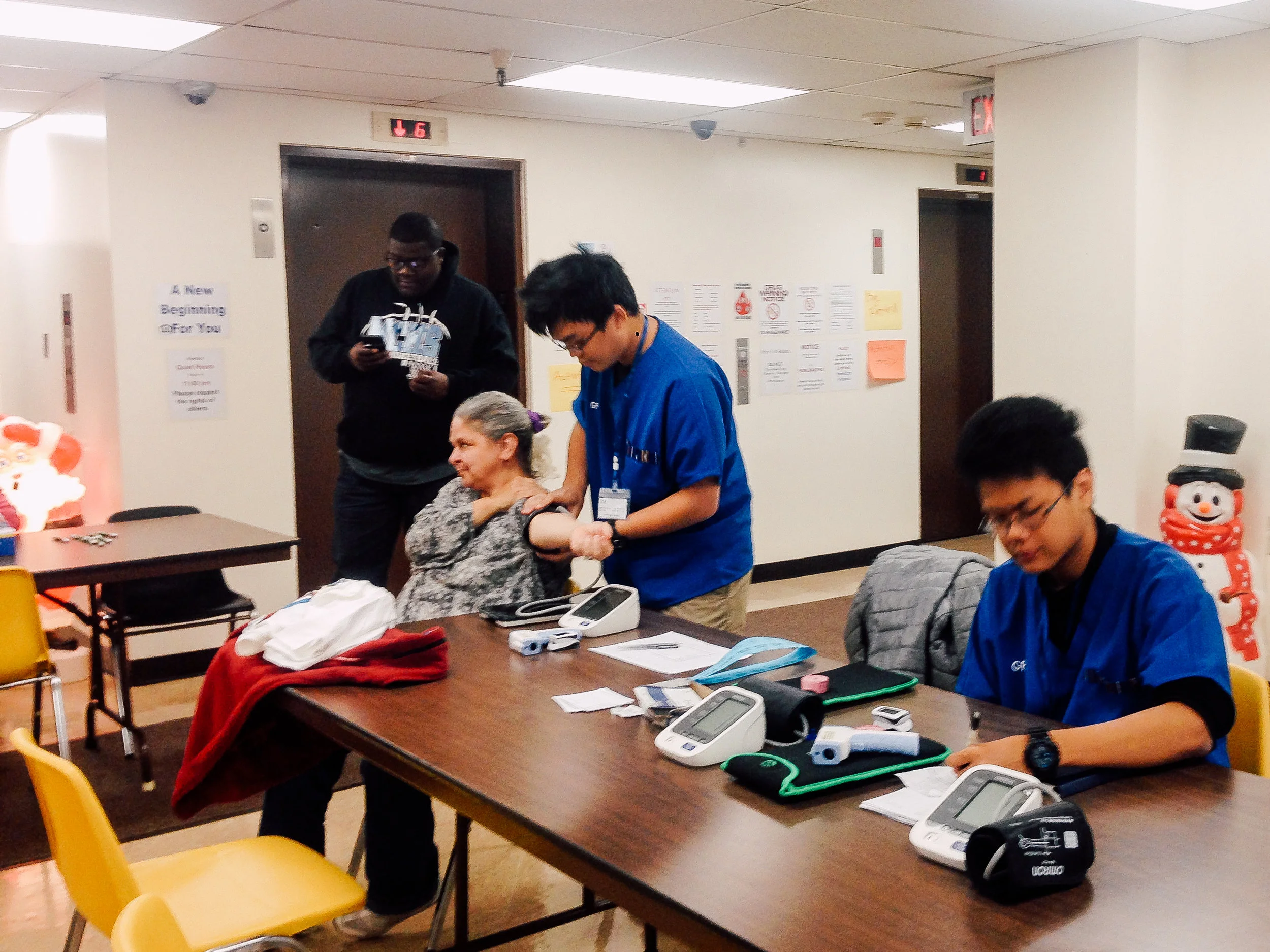 Aw Kinn, one of the participants, helping a patient to take her blood pressure at a health fair