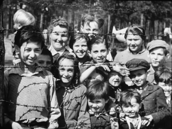 ‘Smiling children through barbed wire.’ Still from footage shot by Sergeant Lewis or Sergeant Lawrie, 18-20 April 1945. © Imperial War Museums (FLM 1467)