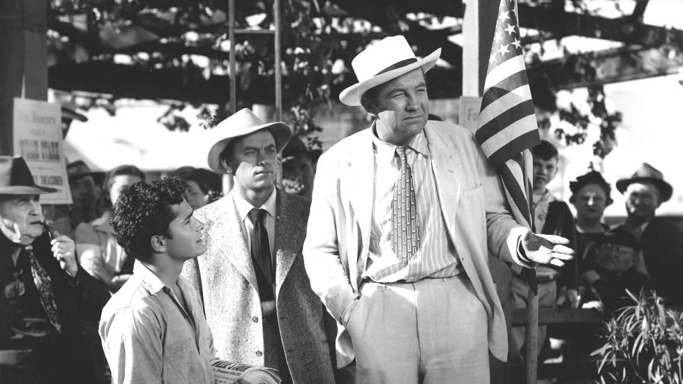 Jack Burden the reporter discovers Stark making a heartfelt if stumbling speech in Kanoma City. Stark’s adopted son Tom (John Derek) is on the left.
