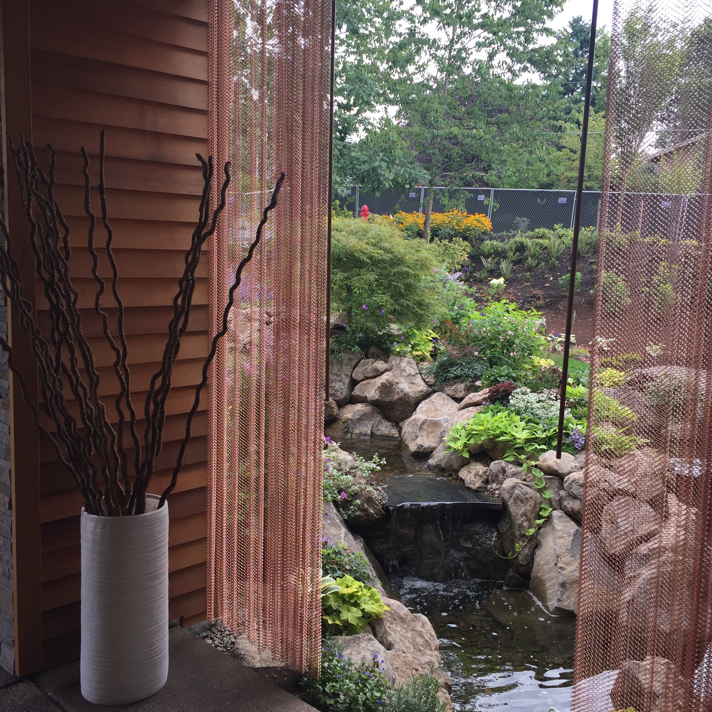 A covered patio with copper-chain drapes overlooked the outdoor pond.