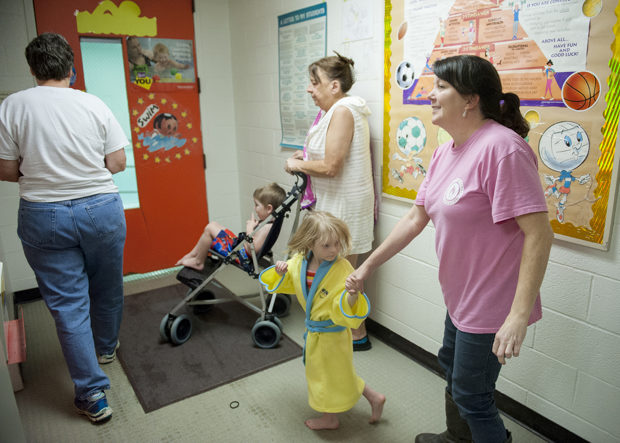 Teacher Gloria Whipple (left) opens up the pool for the class as Braven Windle (in stroller) and Shirley Anderson (bathrobe) are accompanied by Chris McLain and Gini Tabler.