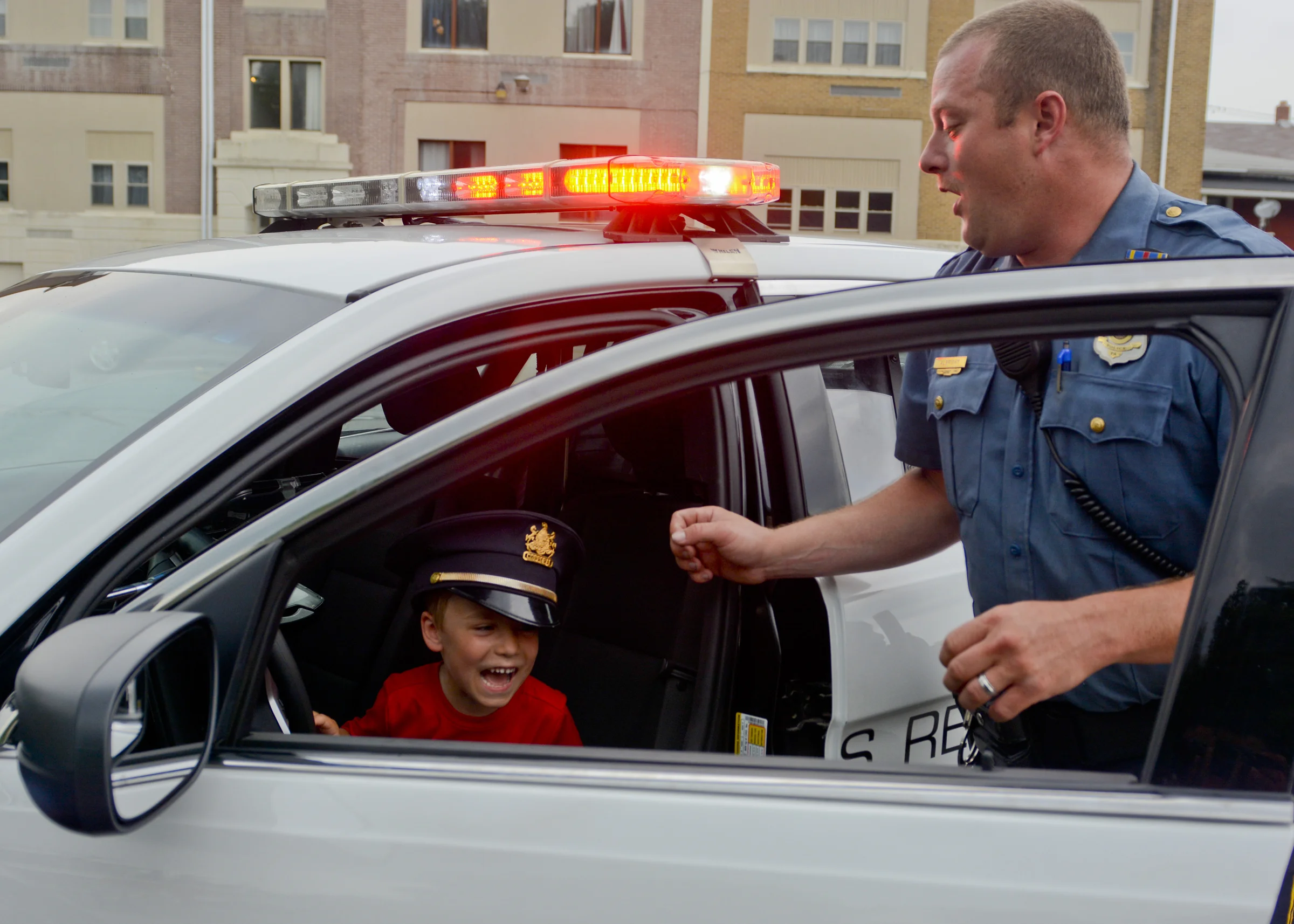 Michael Beitinger, 5, of Sinking Spring laughs after he turned on the police siren as Corporal Danial Albright of the Western Berks Police Department looks to turn it off at an event at the Robesonia Community Library where community members could get up close to firetrucks and other large vehicles on July 13, 2017.
