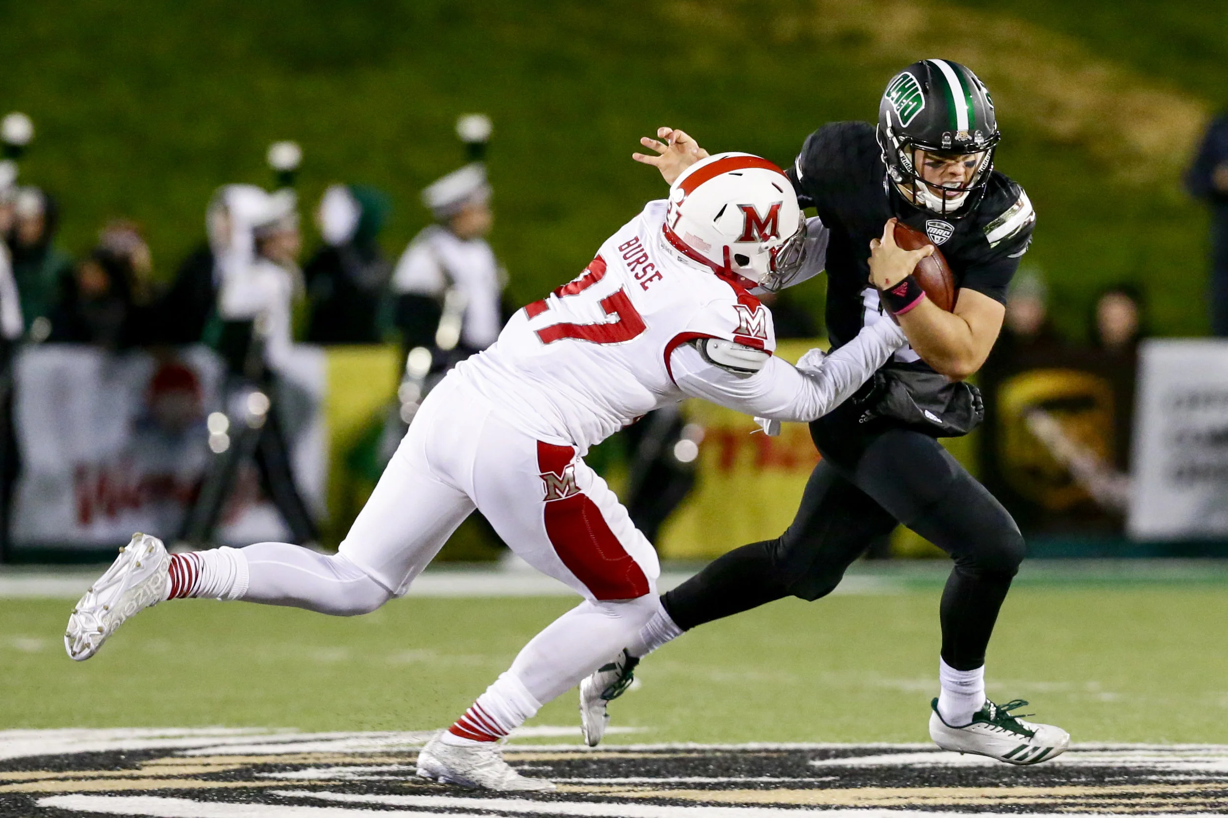 Ohio sophomore quarterback Nathan Rourke (#12) looks to shed the tackle from Miami (OH) sophomore defensive back Kobe Burse (#27) during the first half of the Bobcats' 45-28 win on October 31, 2017.