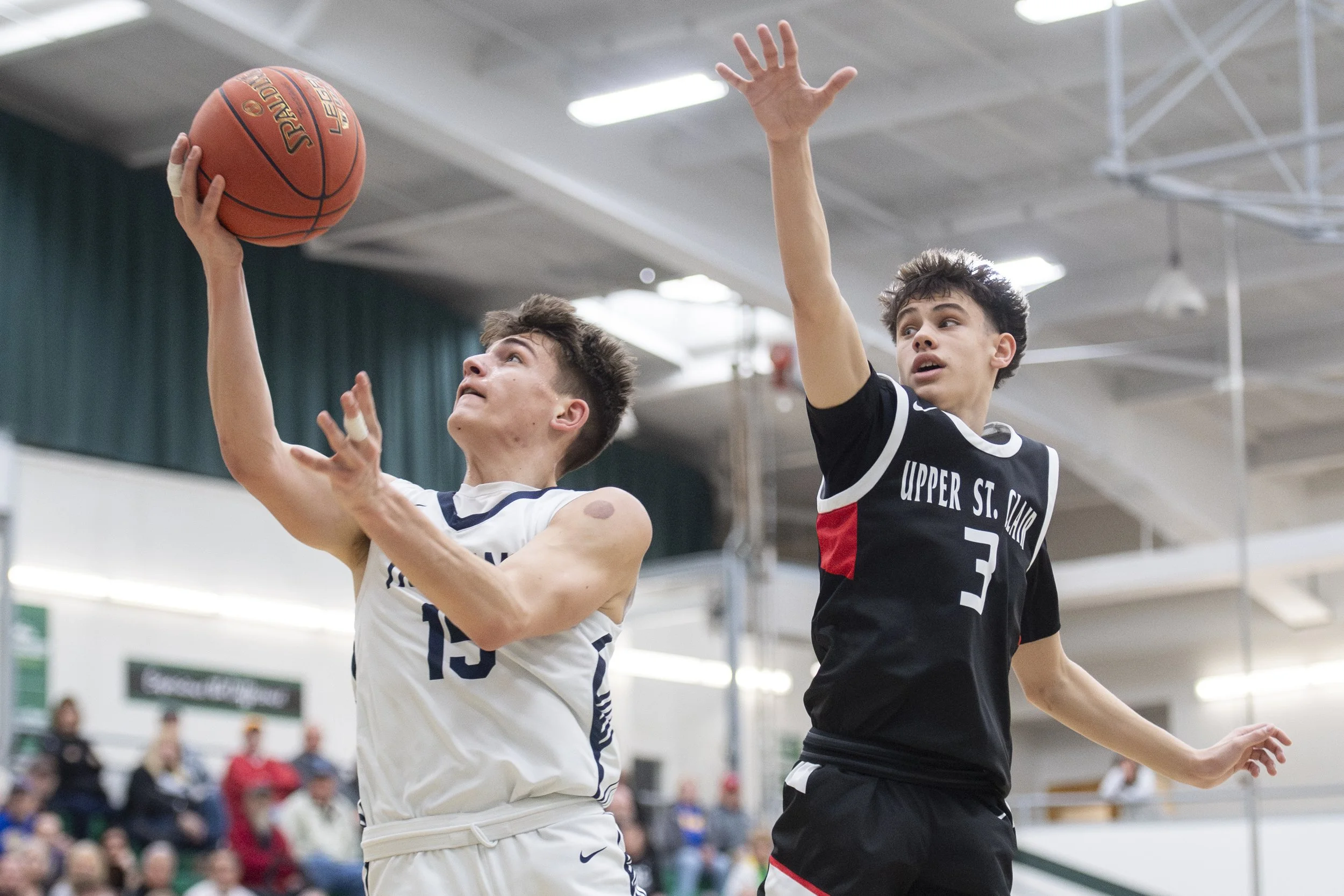  McDowell junior guard Leo Finazzo (#15)  goes in for a layup in front of Upper St. Clair sophomore guard Jude Ausi (#3) in the second quarter of their PIAA Class 6A quarterfinal game at Slippery Rock University on March 15, 2025. USC would win 51-49