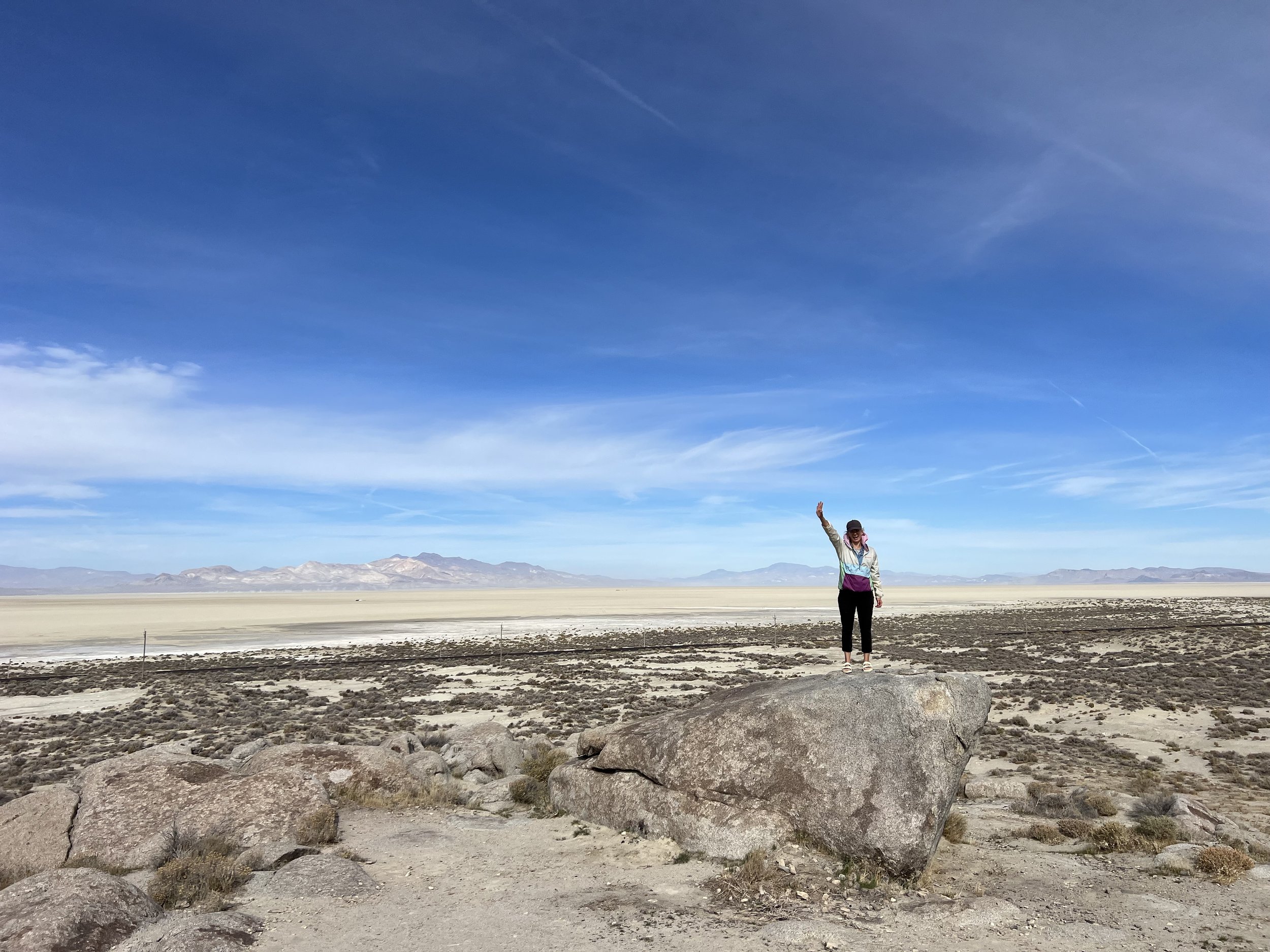 Stephanie outside on a boulder with bright blue sky behind.