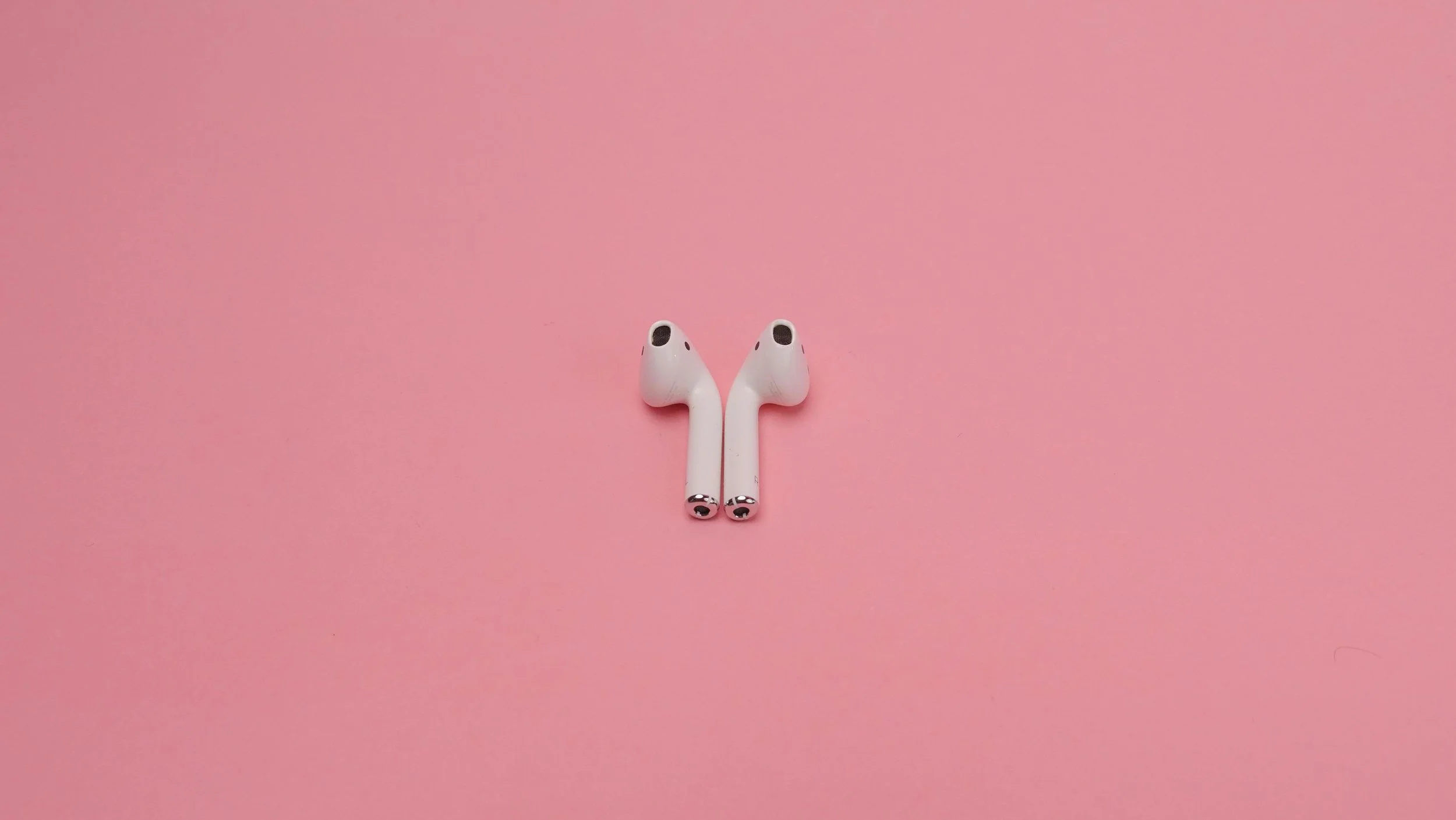 White Wireless Earphones on Pink Surface
