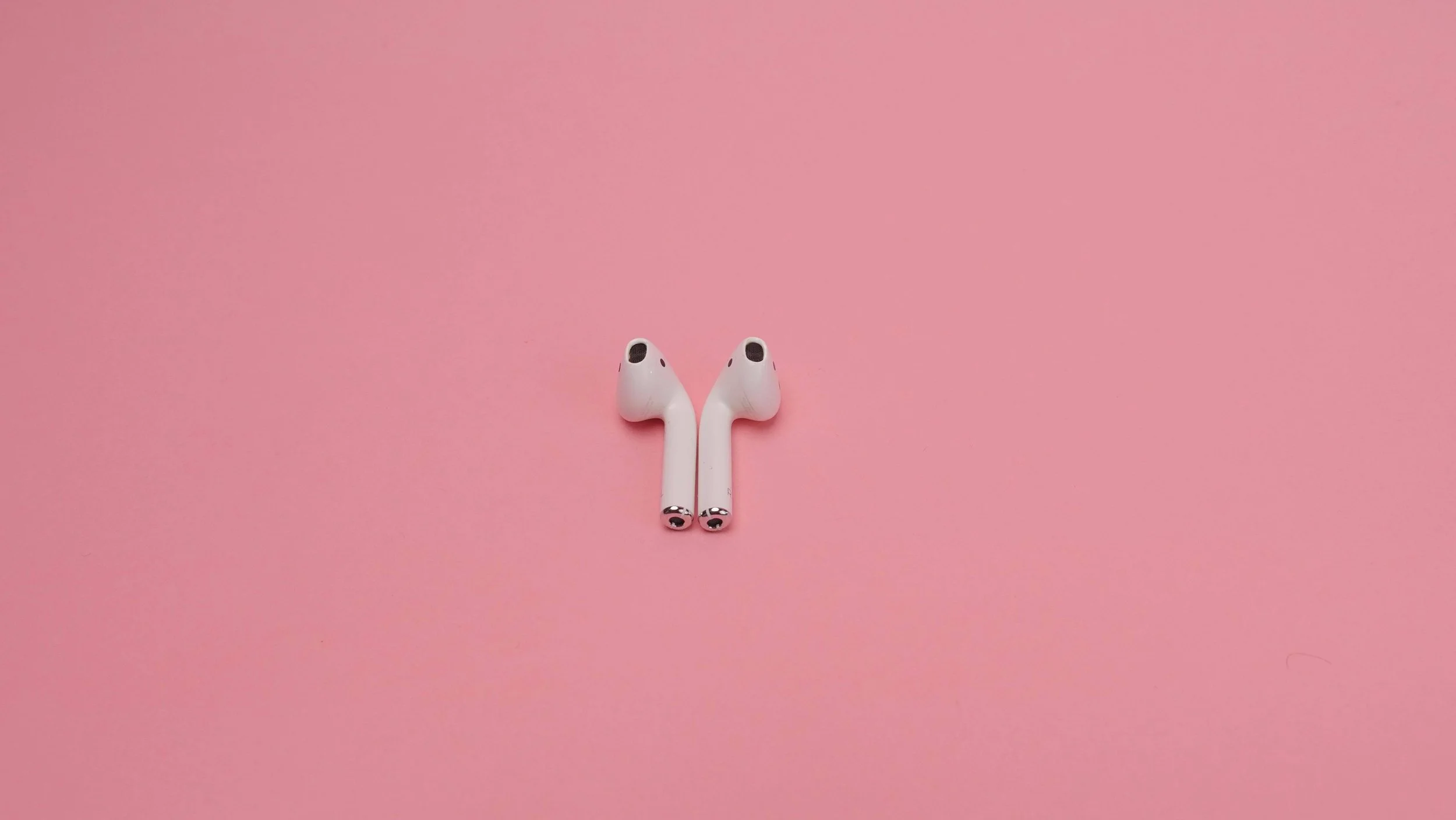 White Wireless Earphones on Pink Surface