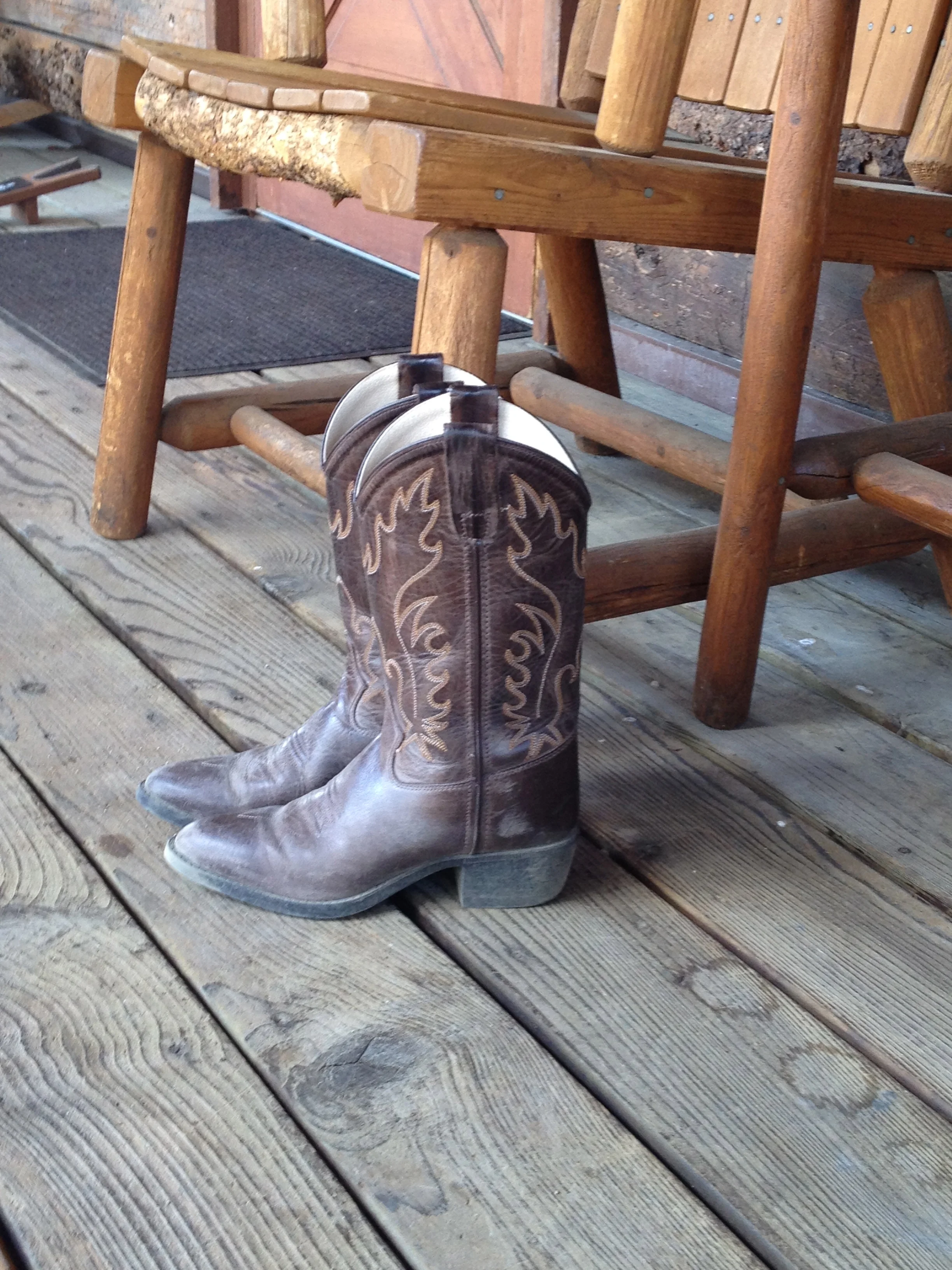 My son's second pair of cowboy boots, resting on our cabin porch after a long day's ride. The heel broke off his first pair on day one, and Vista Verde staff drove into Steamboat and exchanged them for a new pair, so that our vacation would not be i…