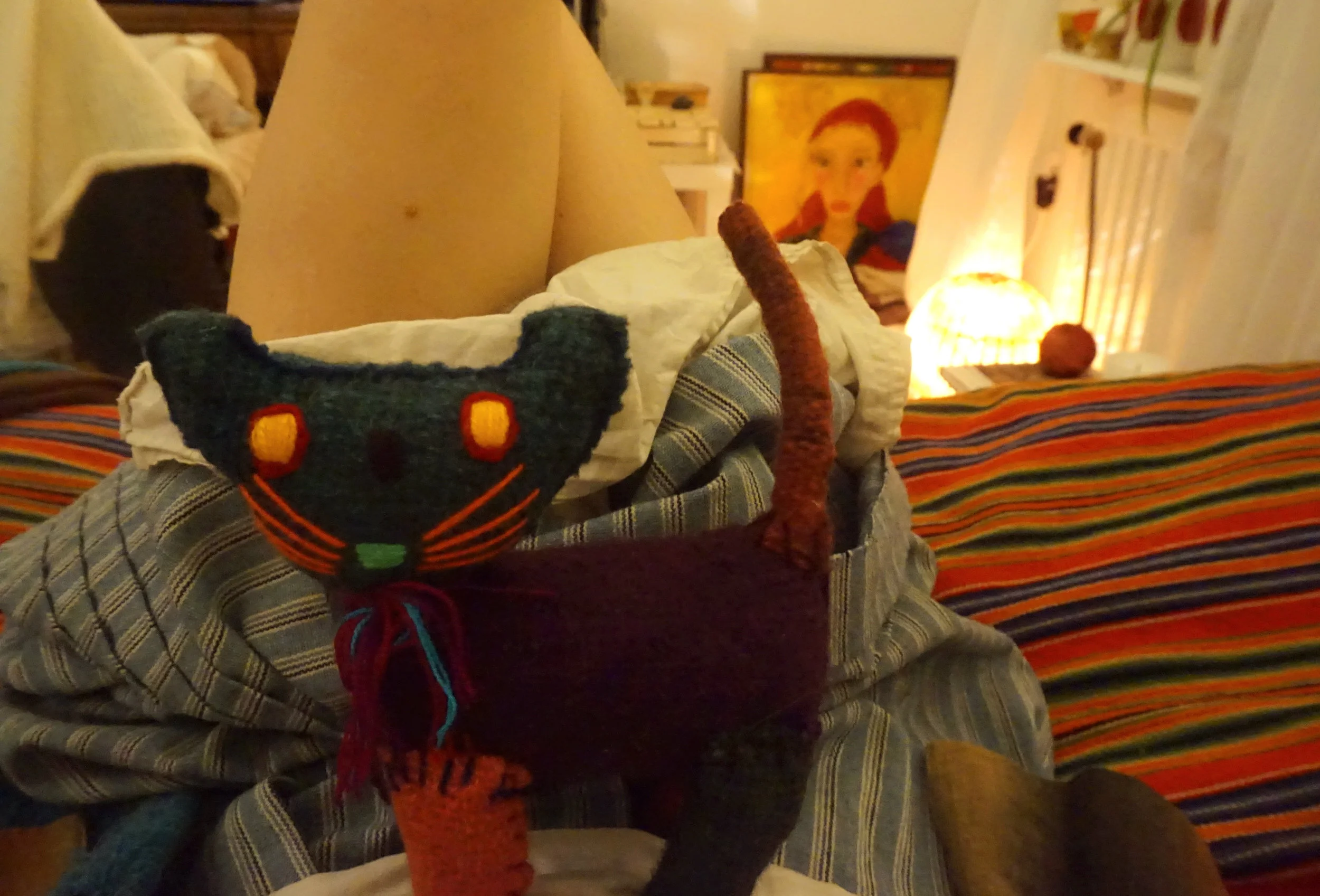 YULEKATT AV MOR I FAMN, OKLART SJÄLVPORTRÄTT SKYMTANDE I BAKGRUND.