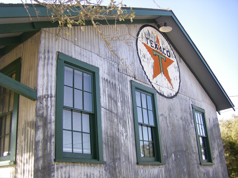 The Texaco warehouse at the rear of the lot was built in Spur, Texas in 1928 and that company opened its agency in the building on January 4, 1929. Spur is located about 70 miles east of Lubbock, and this structure sat at the very end of the line of the Stamford & Northwestern Railroad, which reached the community in 1909. This rail line would become a part of the Burlington Line System in later years. The warehouse was built to receive bulk shipments of gasoline, kerosene and lubricating oil, all delivered by rail at a time when there were no paved roads serving the community, and was one of more than 2000 local agencies serving what was then called “The Texas Company” but later known simply as “Texaco”. The primary customers of this agency included many large ranches in the area. Within 50 years the agency would close, a victim of the same consolidation seen by the railroads, and the building sat vacant for 20 years until moved here in 1999. 