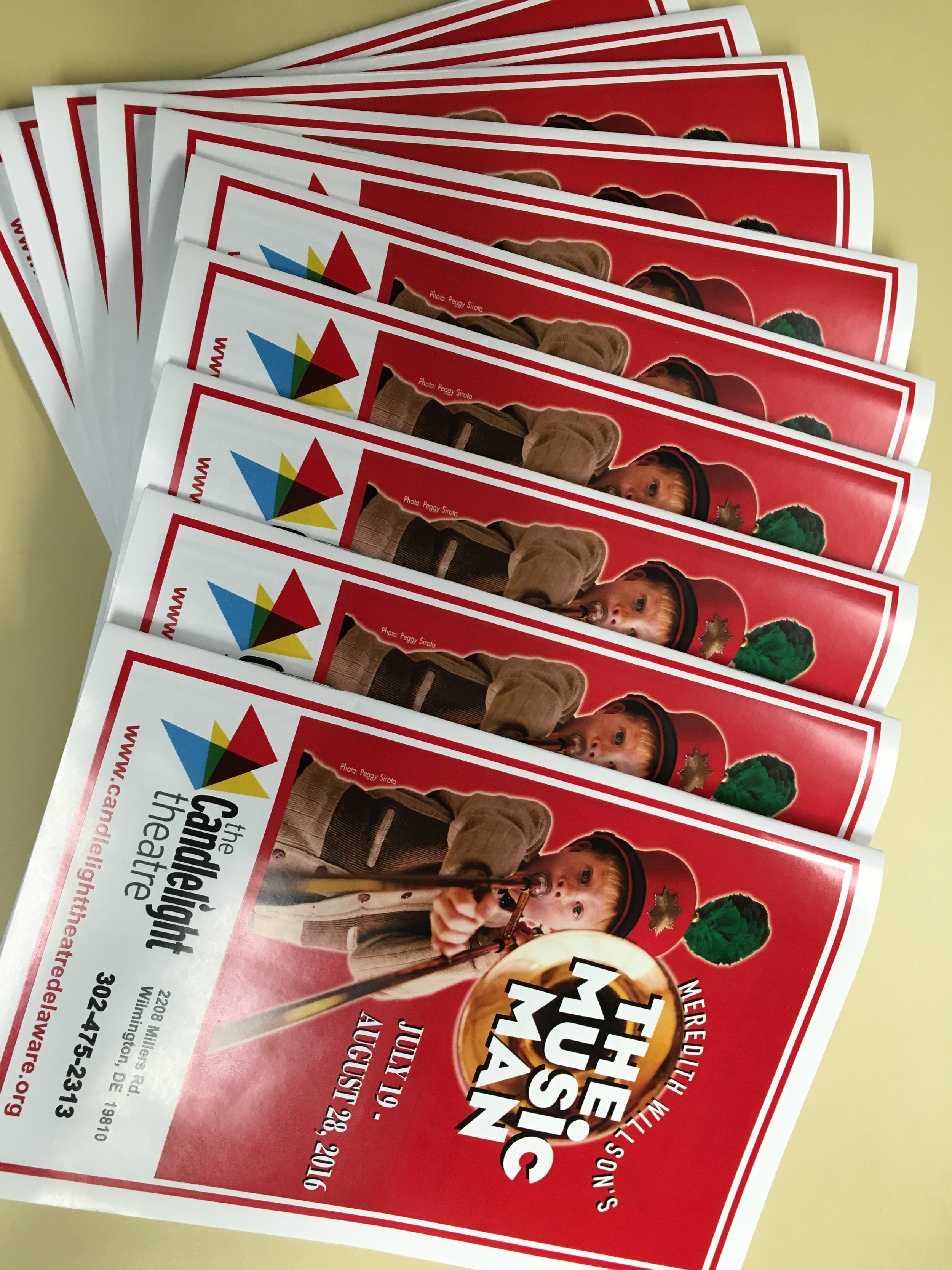 Event flyers for 'The Musical'; features a young boy wearing a costume and holding a pipe, with red and white colors and a colorful logo on the top left corner, providing event dates and location information.