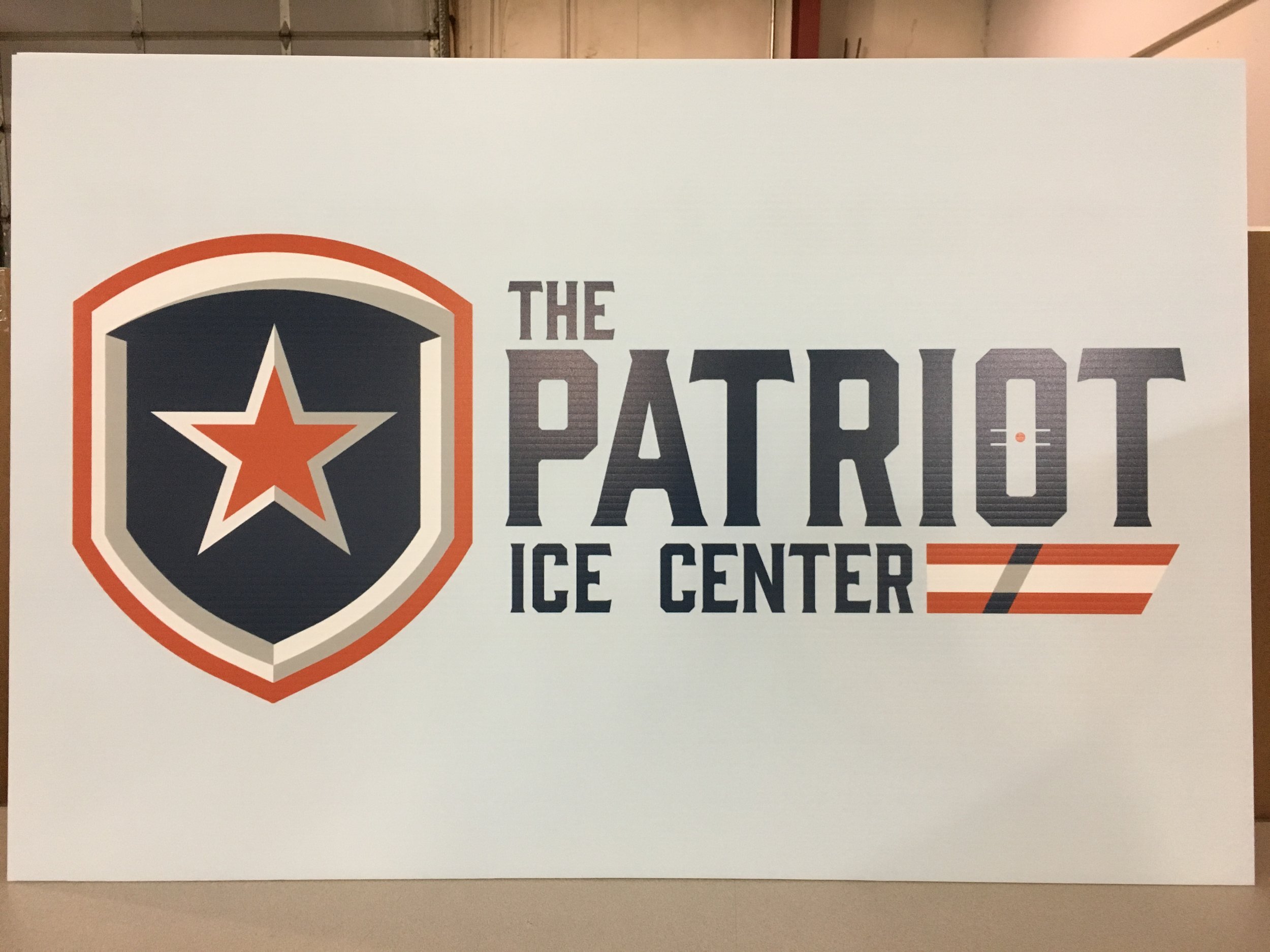 Sign for The Patriot Ice Center featuring a shield with a star emblem and stylized stripes.