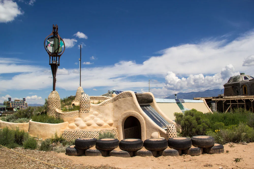 Una earthship equipada con un molino de viento y placas solares.